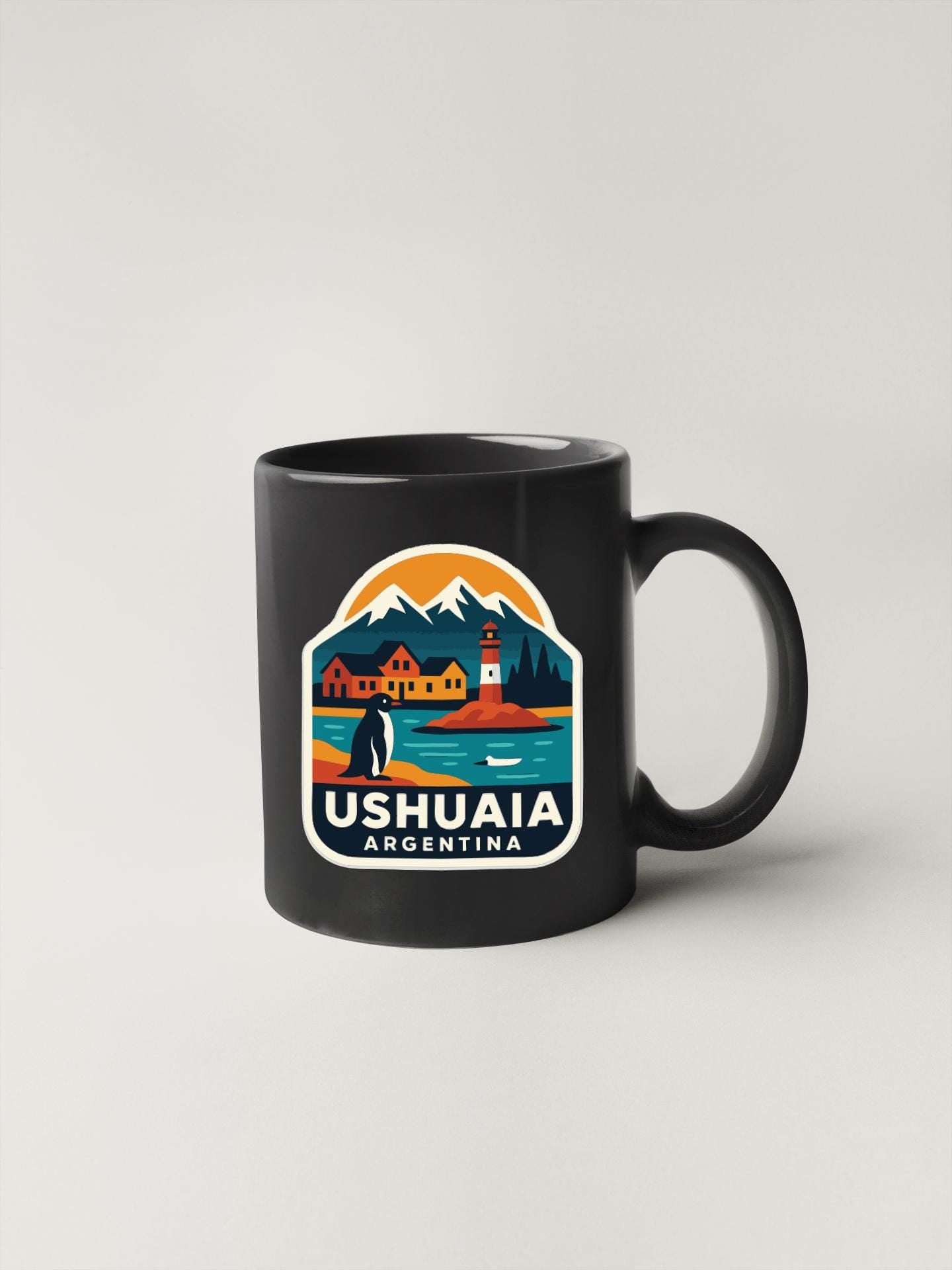 A black coffee mug with a colorful graphic design depicting a scenic landscape with mountains, a lighthouse, and a penguin.
