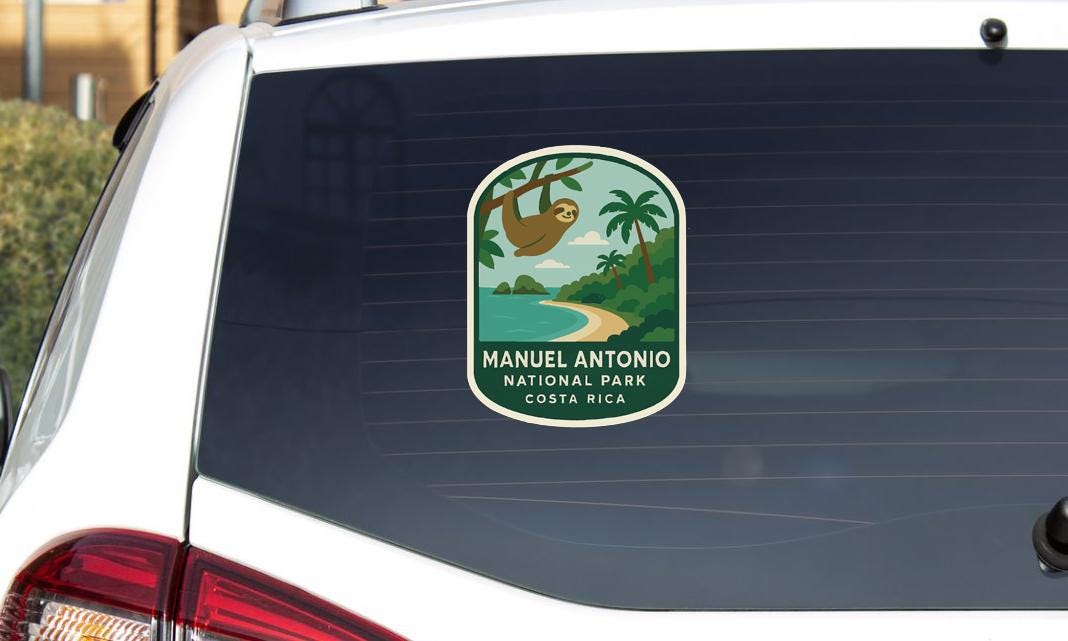 A sticker on the rear window of a car, depicting a sloth hanging from a tree in a tropical landscape.