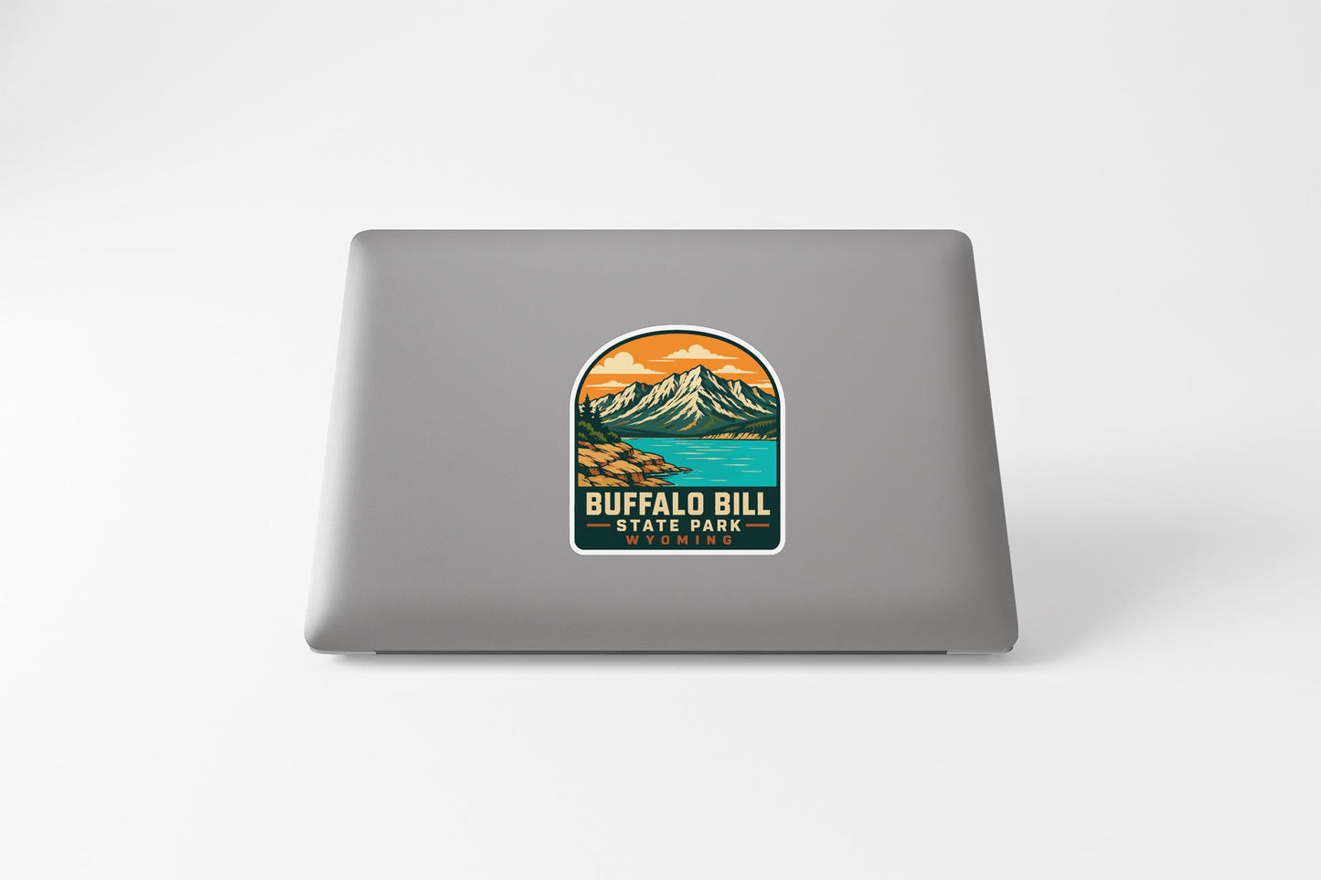 A sticker on the back of a laptop, depicting a mountain landscape with a lake and mountains in the background.