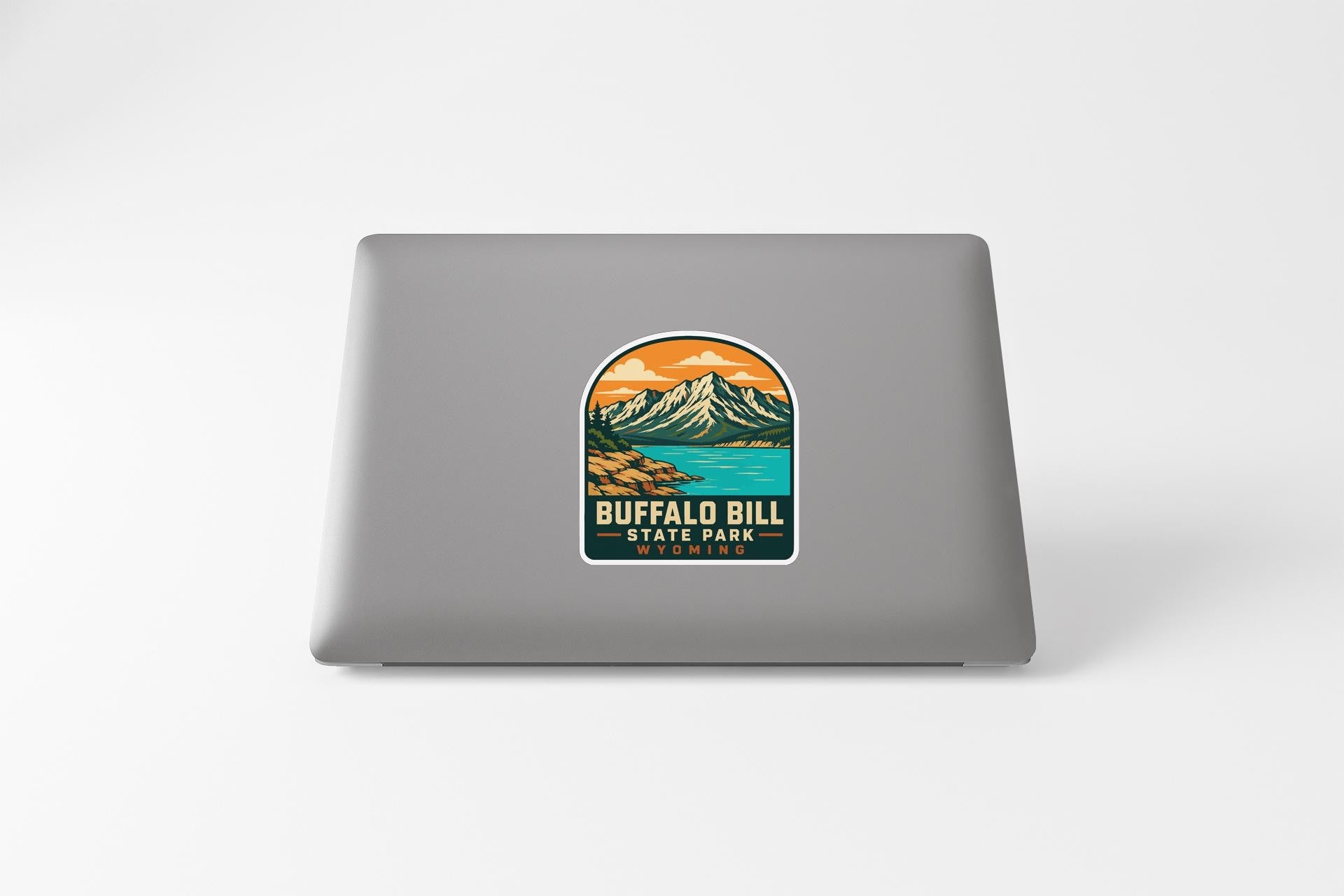 A sticker on the back of a laptop, depicting a mountain landscape with a lake and mountains in the background.