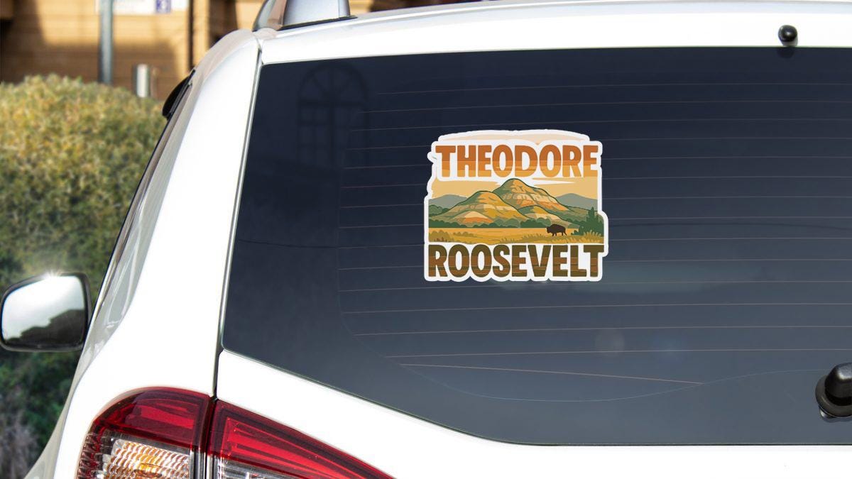 A sticker on the rear window of a car that says "THEODORE ROOSEVELT".