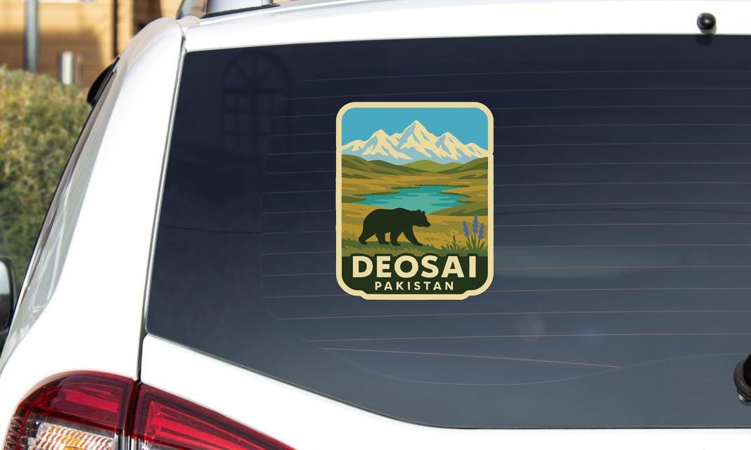 A sticker on the rear window of a car that features a bear and mountains, along with the text "DEOSAI PAKISTAN".