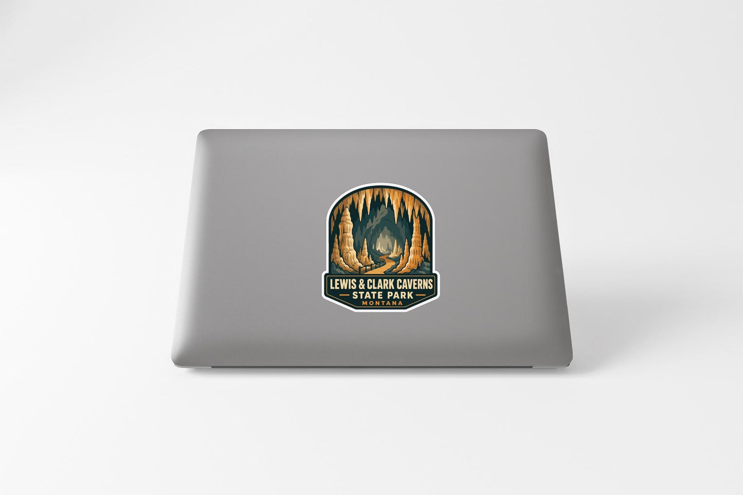 A sticker on the back of a laptop, featuring an illustration of a cave with a sign that reads "LEWIS & CLARK CAVENS STATE PARK".