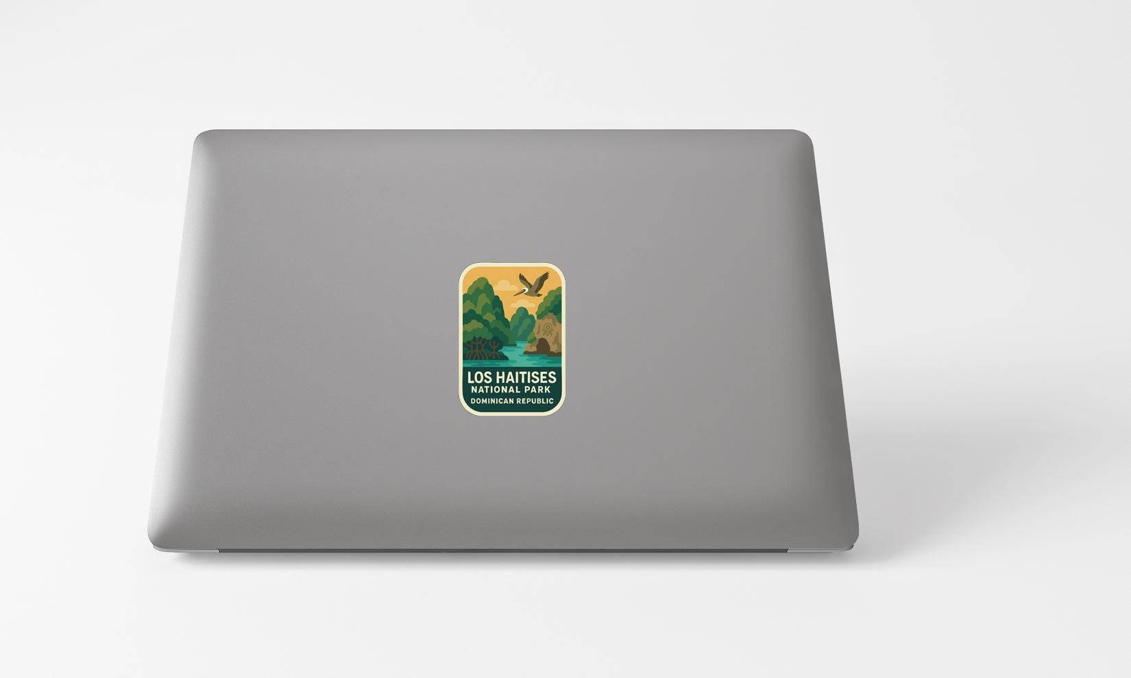 A sticker on the back of a laptop, featuring an illustration of a bird and a landscape with trees.