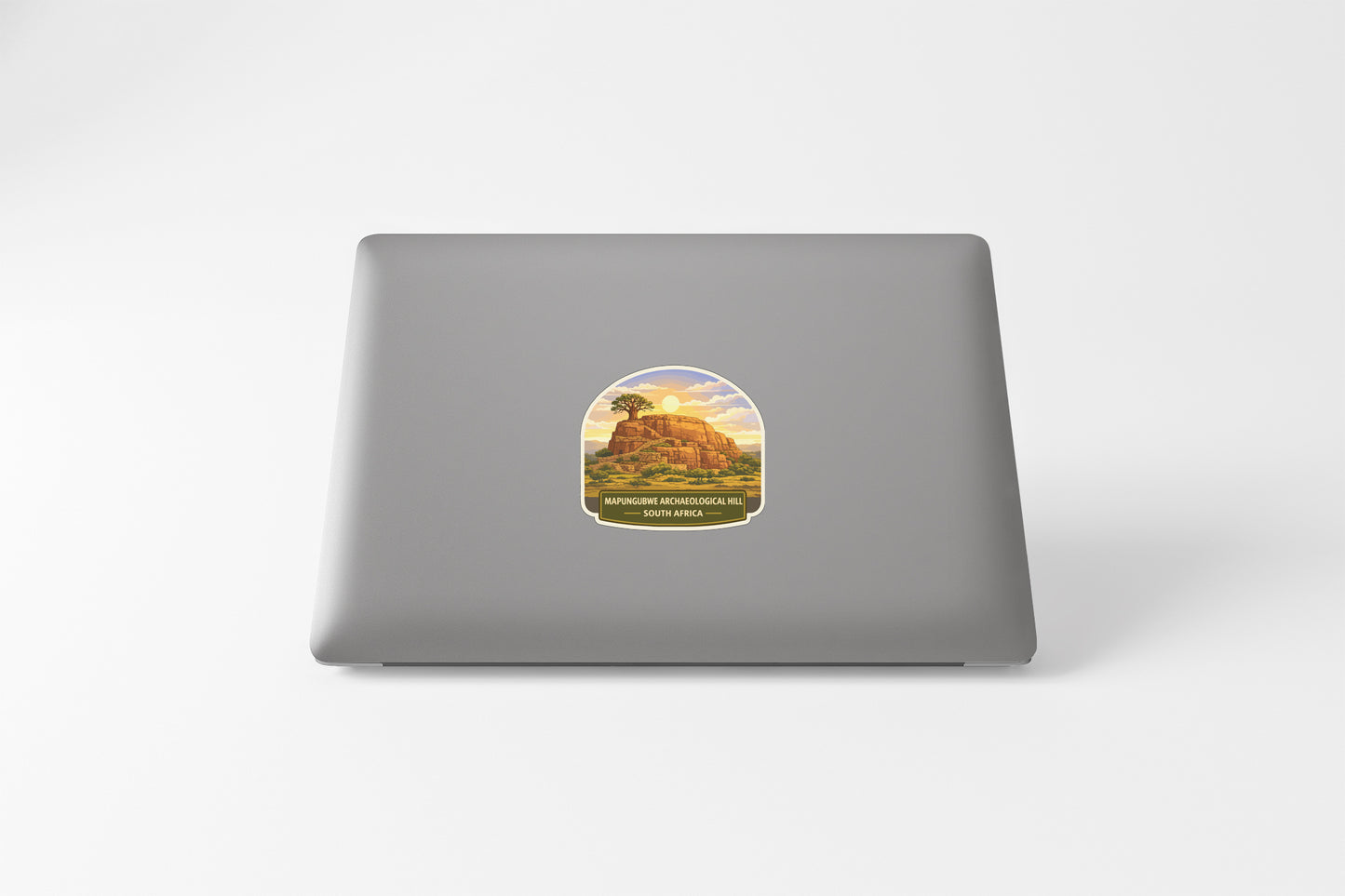 A sticker depicting a mountain landscape with a tree on top is placed on the back of a laptop computer.
