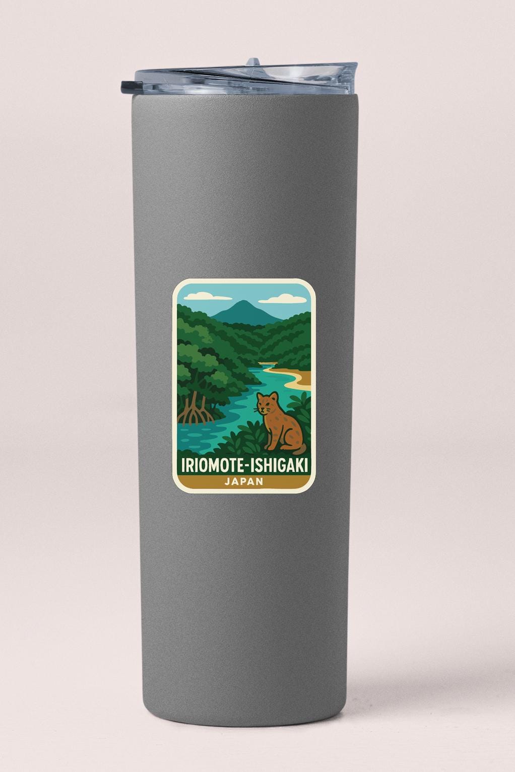 A gray insulated tumbler with a sticker depicting a scenic landscape featuring a river, mountains, and a brown bear.