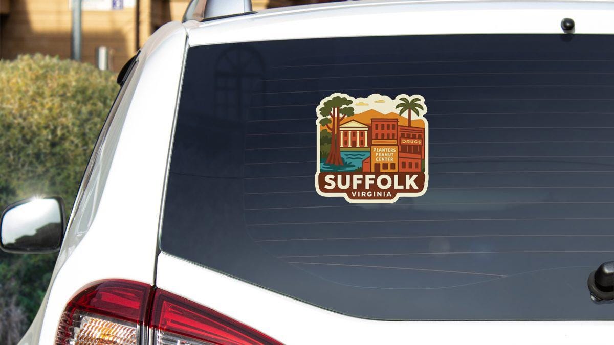 A sticker on the rear window of a white car, depicting a scenic view of the town of Suffolk, Virginia.