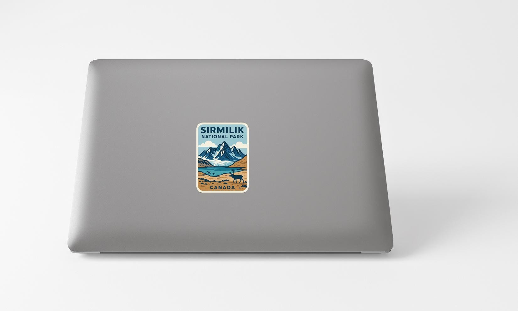 A sticker on the back of a laptop, featuring a mountain landscape with a lake and a bear.