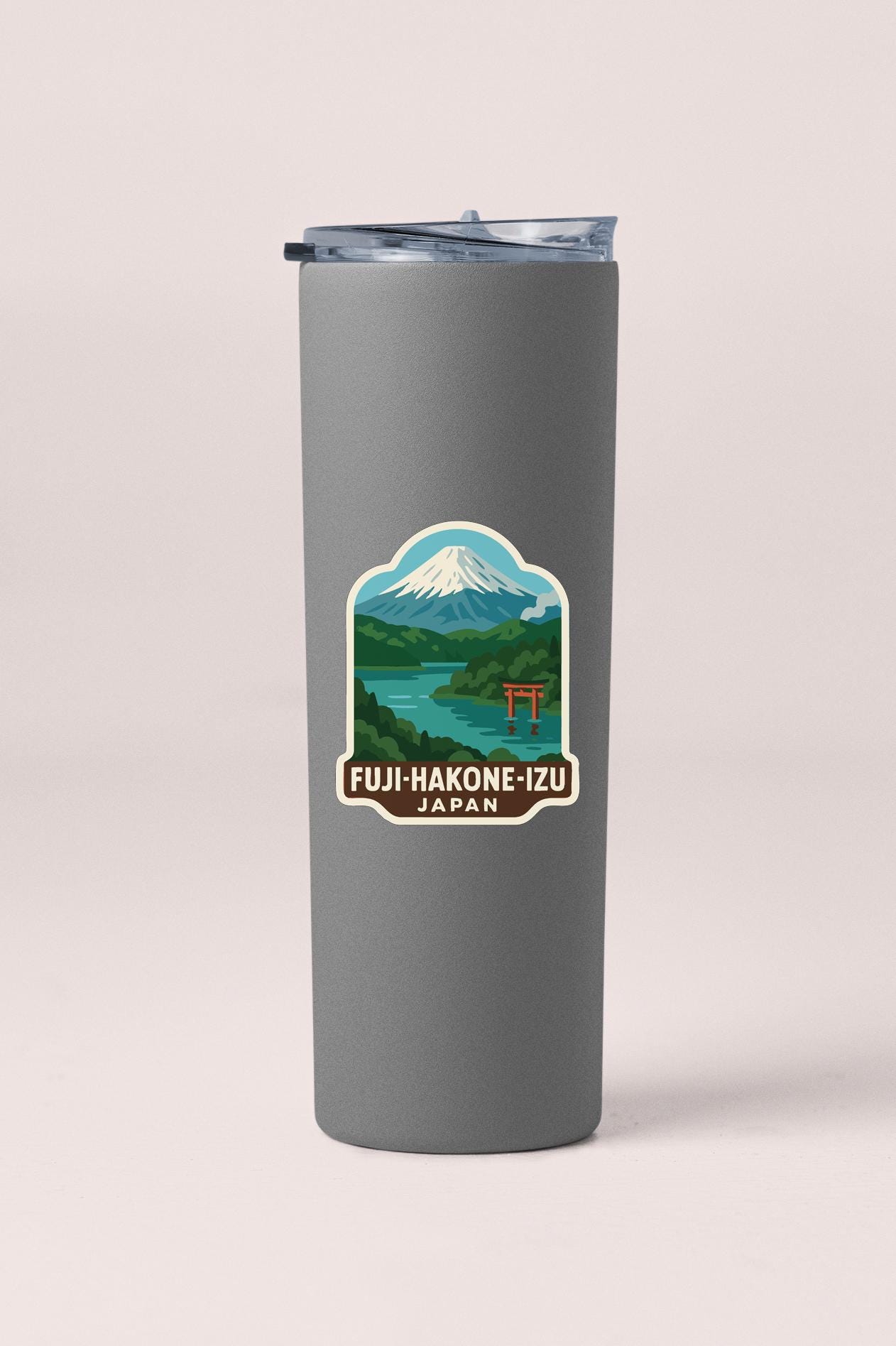 A gray tumbler with a sticker depicting a mountain landscape and a temple in Japan.