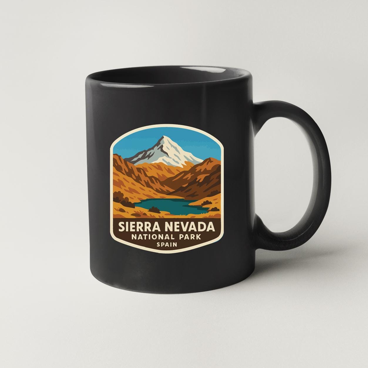 A black coffee mug with a graphic design depicting the Sierra Nevada National Park in Spain.
