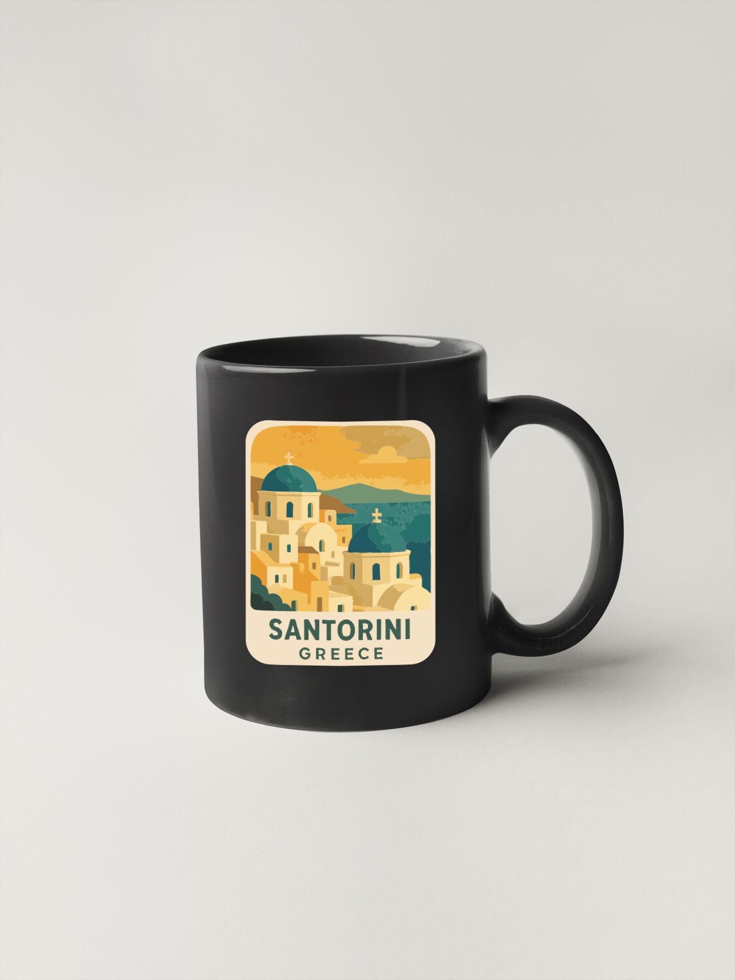A black coffee mug with a graphic design depicting the city of Santorini, Greece.