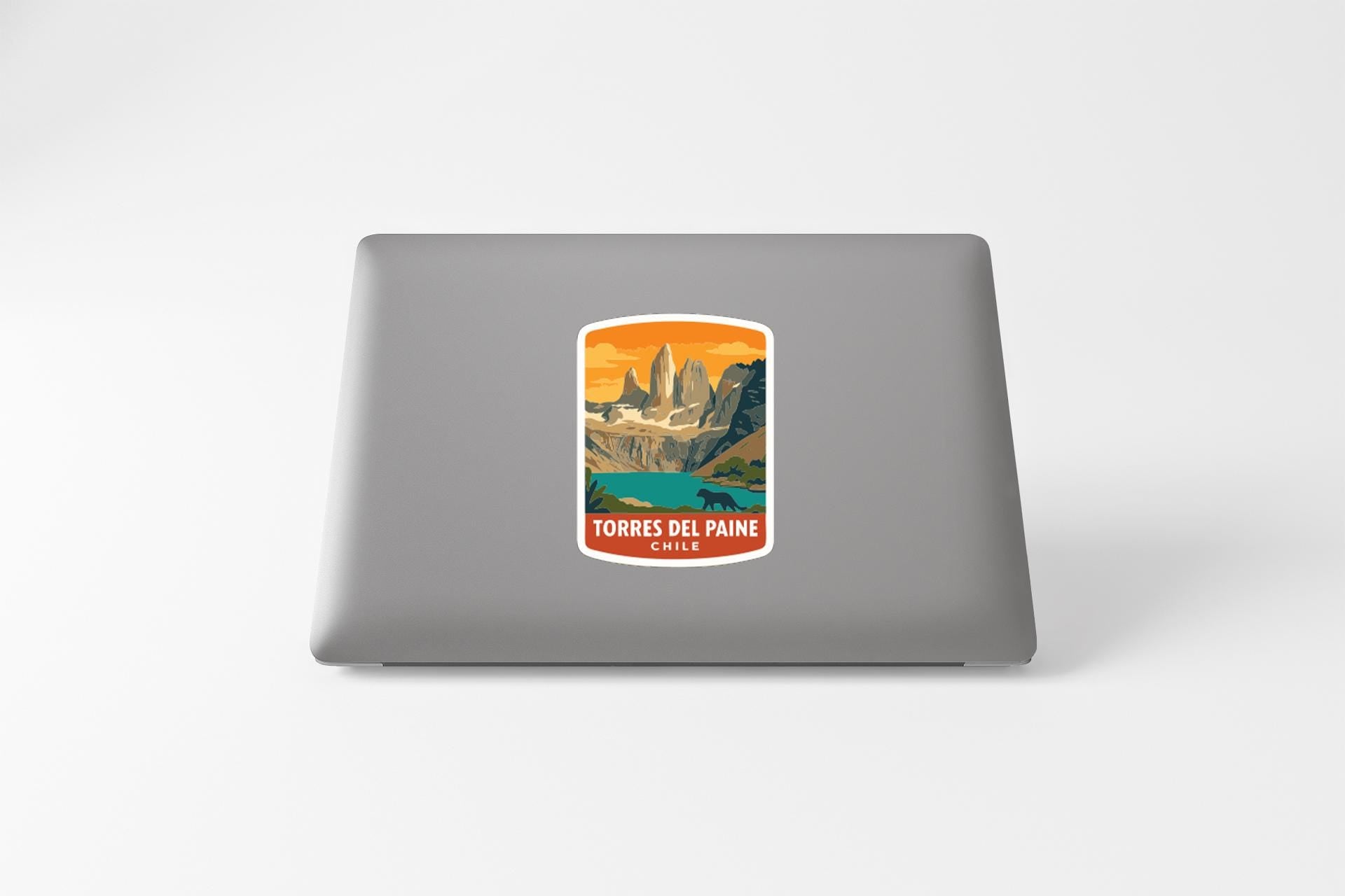 A sticker on the back of a laptop, depicting a mountain landscape with a lake in the foreground.