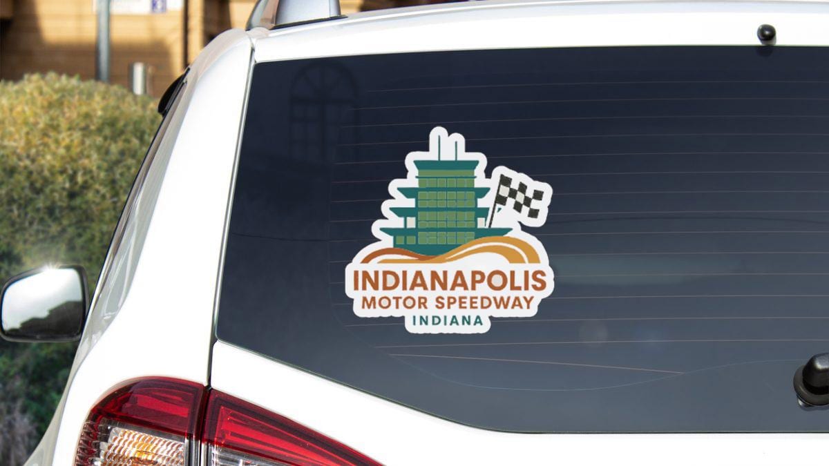 a sticker on the rear window of a white vehicle, displaying the logo for the Indianapolis Motor Speedway in Indiana.
