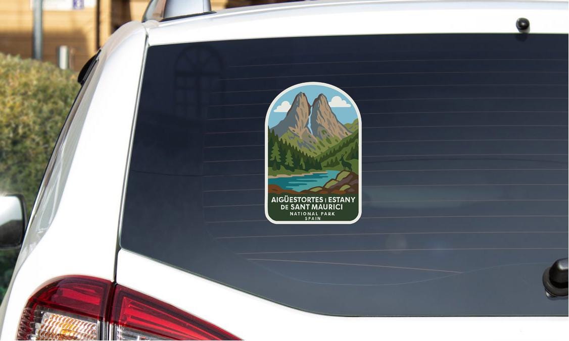 a sticker on the rear window of a car, depicting a mountain landscape with a lake and forest.