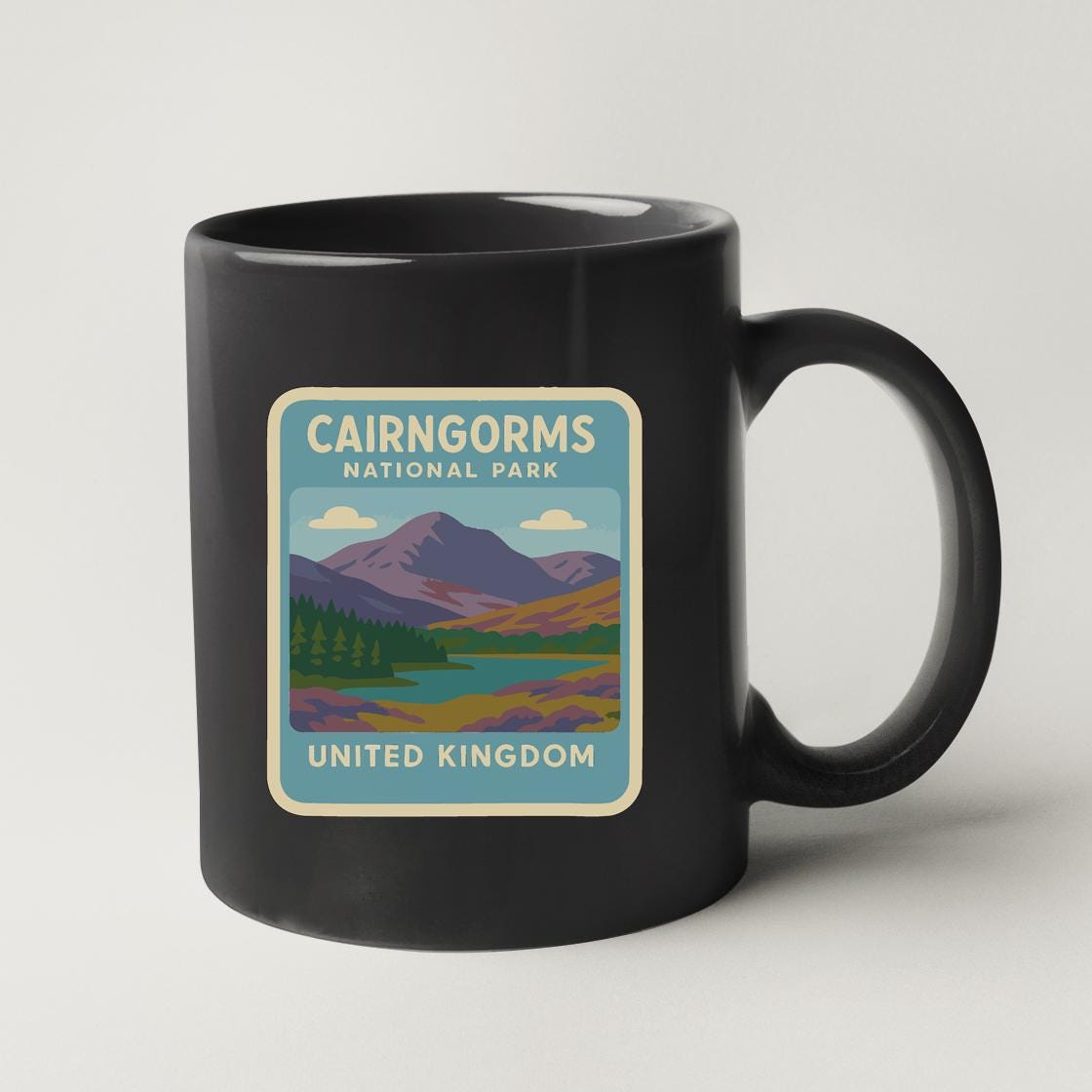 A black coffee mug with a label that says "CAIRNGORMS NATIONAL PARK UNITED KINGDOM".