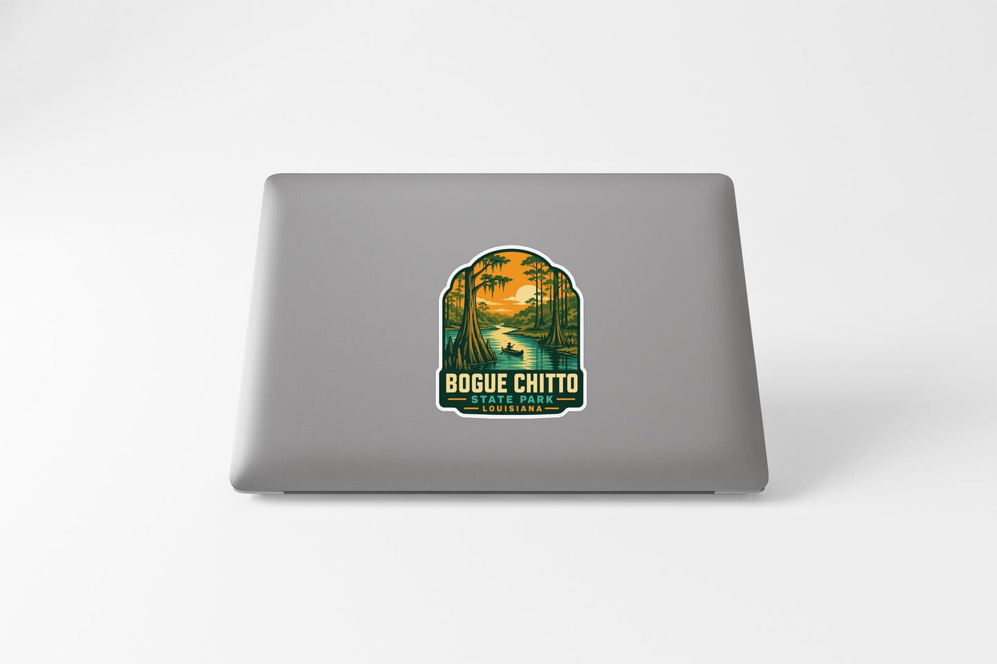 A sticker on the back of a laptop, depicting a scenic landscape with a river and trees.