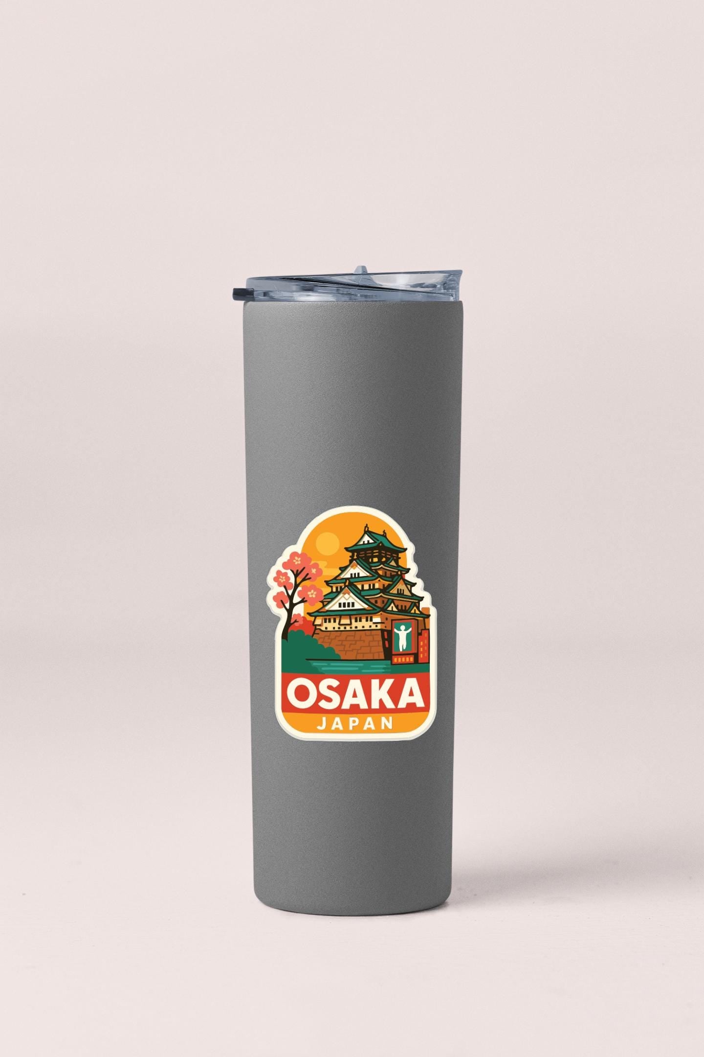 A gray insulated tumbler with a sticker depicting the Osaka, Japan, castle.