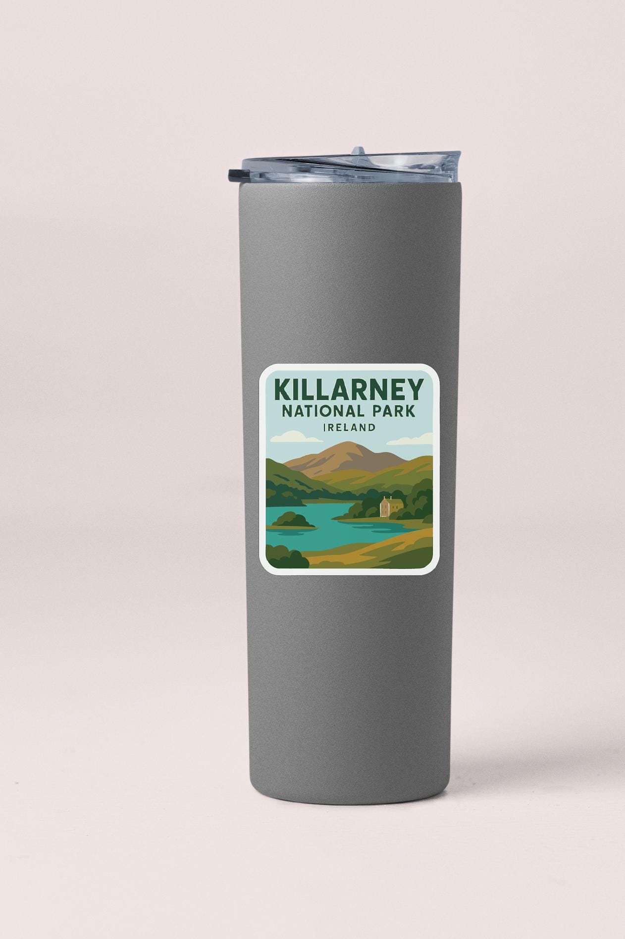 A gray tumbler with a sticker depicting a scenic landscape of Killarney National Park, Ireland.