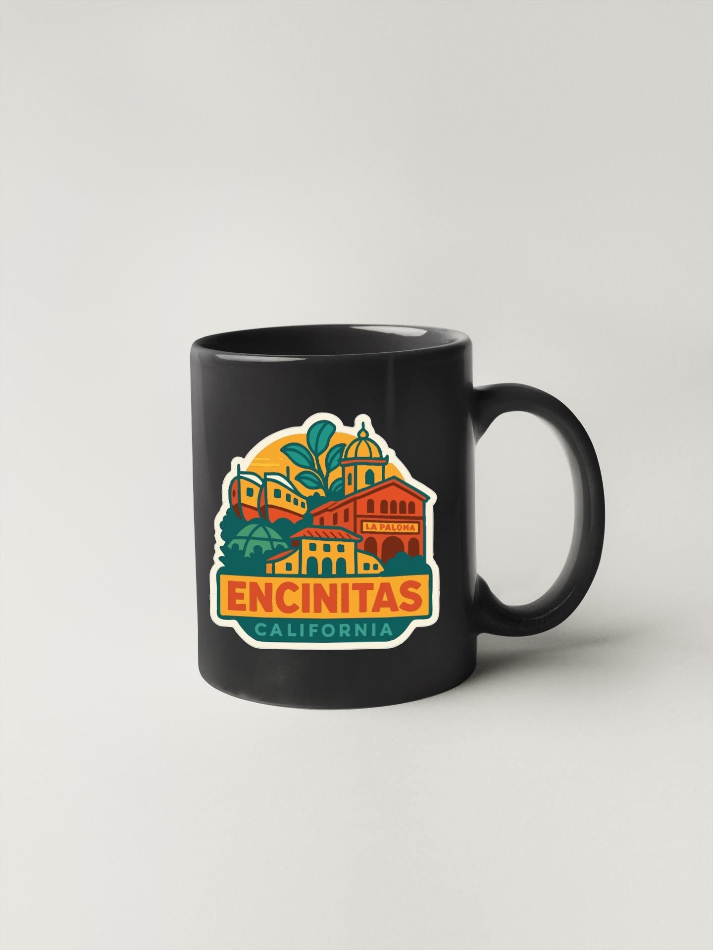 A black coffee mug with a colorful graphic design depicting a cityscape and the text "ENCINITAS, CALIFORNIA" printed on it.