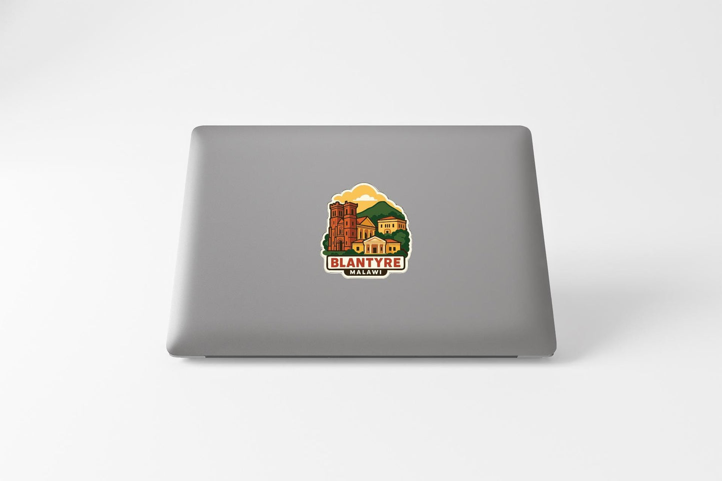 a sticker with a graphic of a building and the text "BLANTYRE MALWALE" on the back of a laptop.
