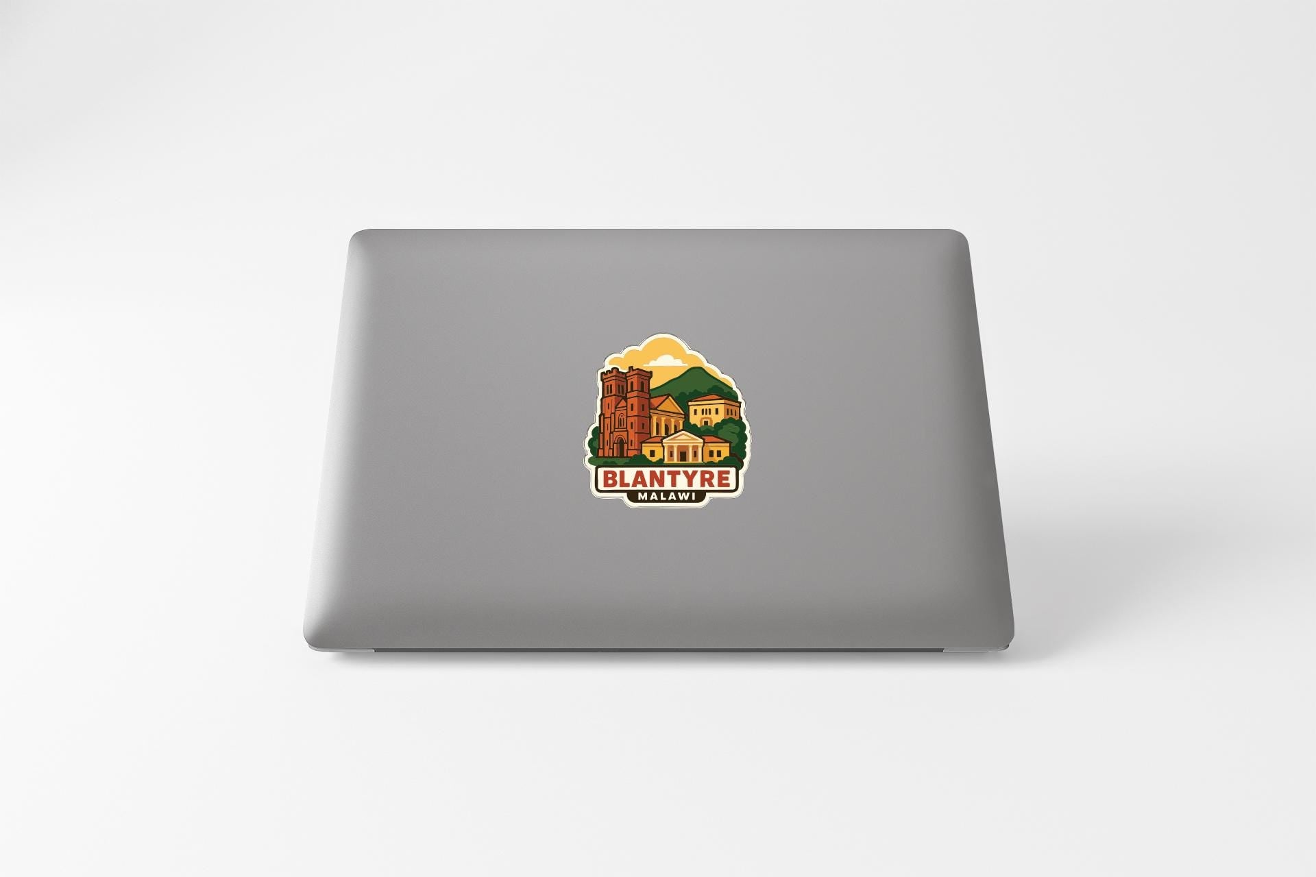 a sticker with a graphic of a building and the text "BLANTYRE MALWALE" on the back of a laptop.
