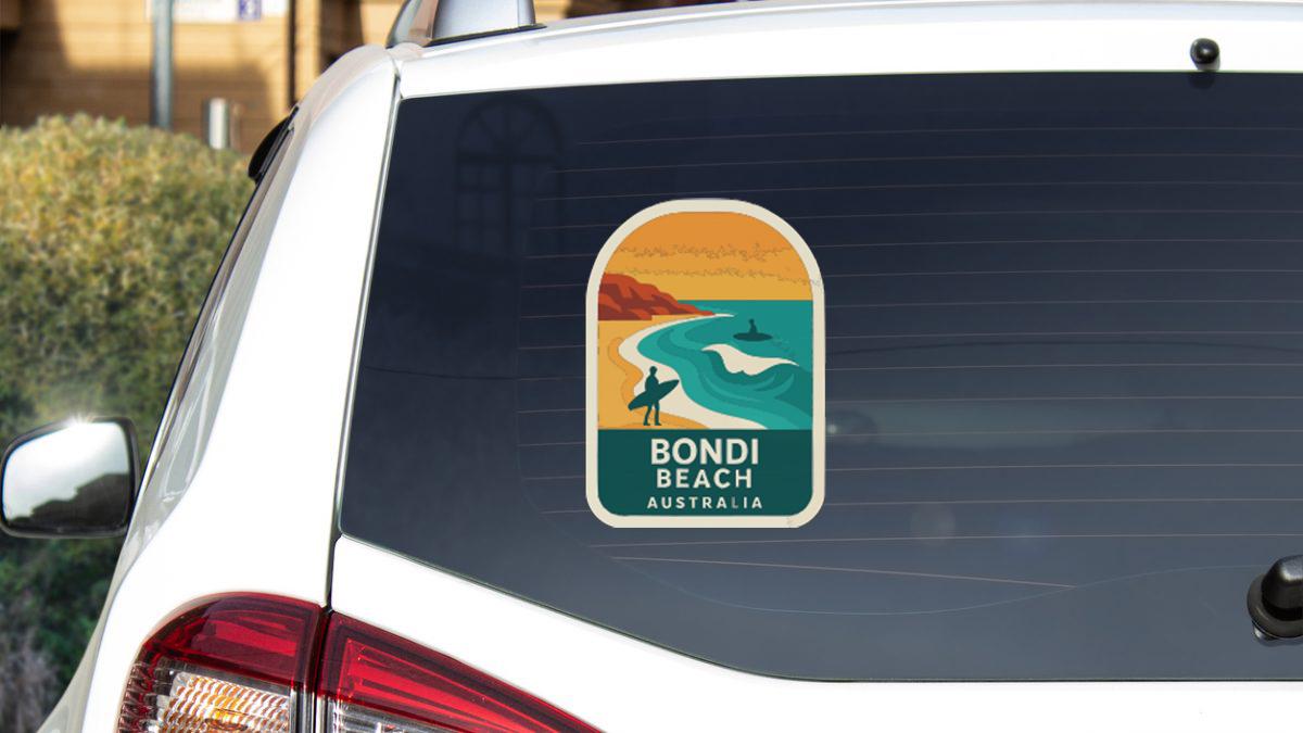 A sticker on the rear window of a white car, depicting a beach scene with a surfer and the text "BONDI BEACH AUSTRALIA".