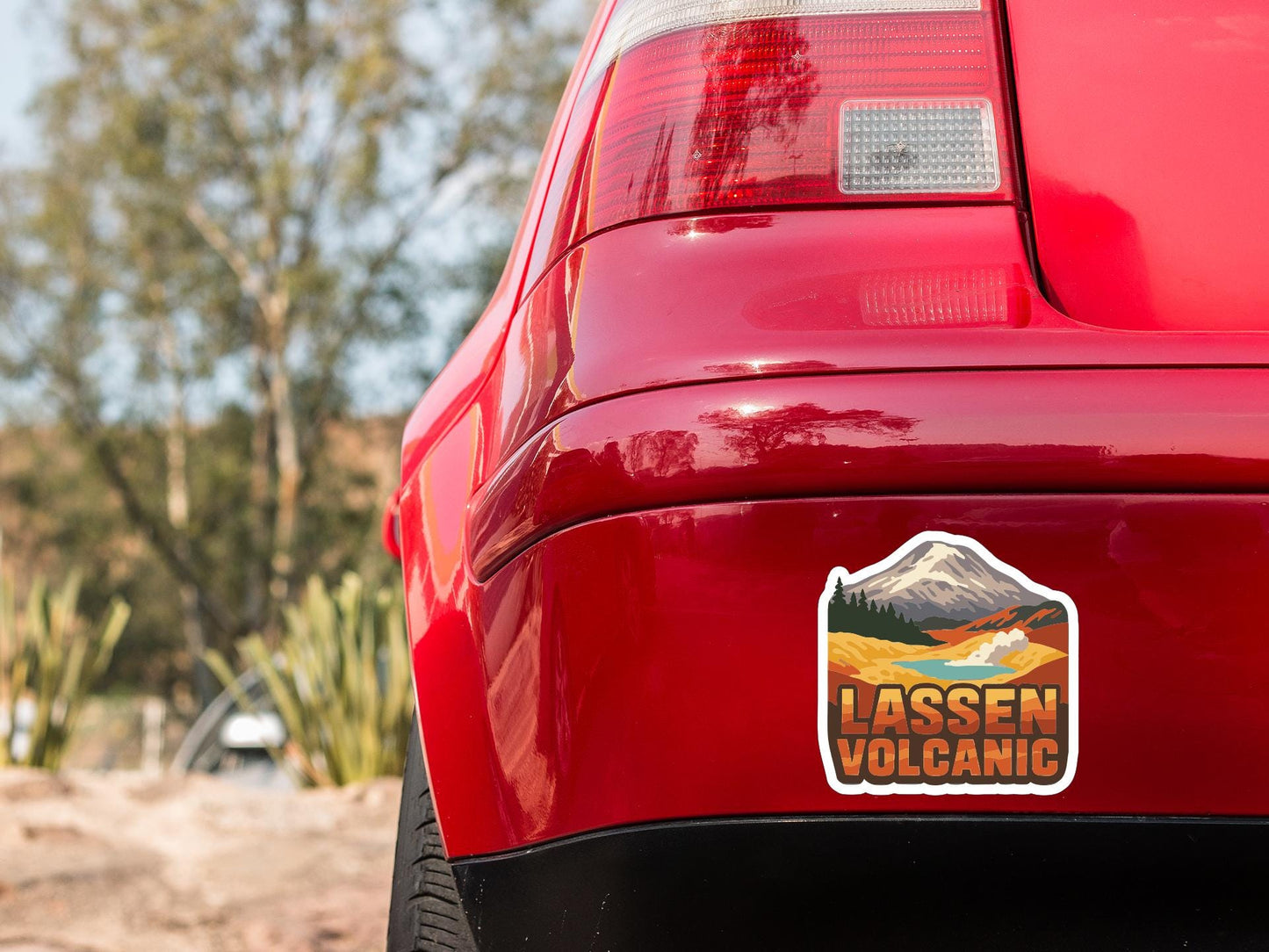 the rear end of a red car with a sticker on the trunk that says "LASSEN VOLCANIC".