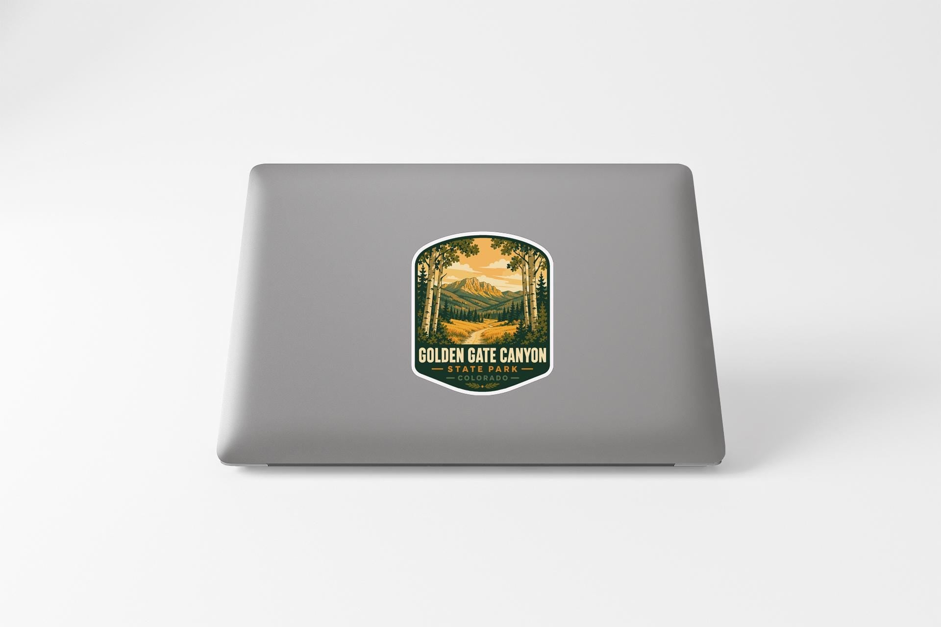 A sticker on the back of a laptop, depicting a scenic landscape with mountains and a river.