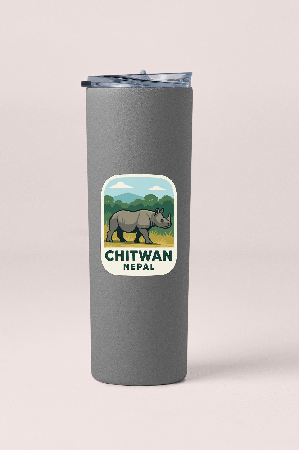 A gray tumbler with a sticker depicting a rhinoceros and the text "CHITWAN NEPAIL" printed on it.