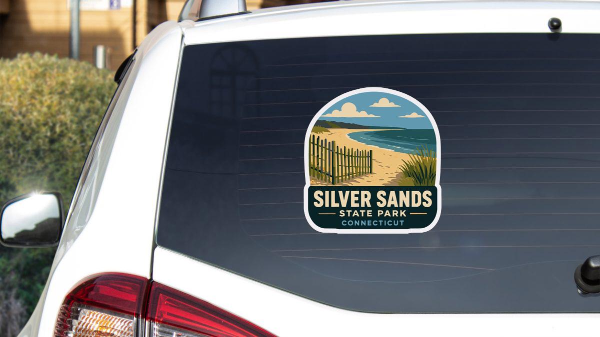 A sticker on the rear window of a white car, depicting a beach scene with a wooden fence and a body of water.