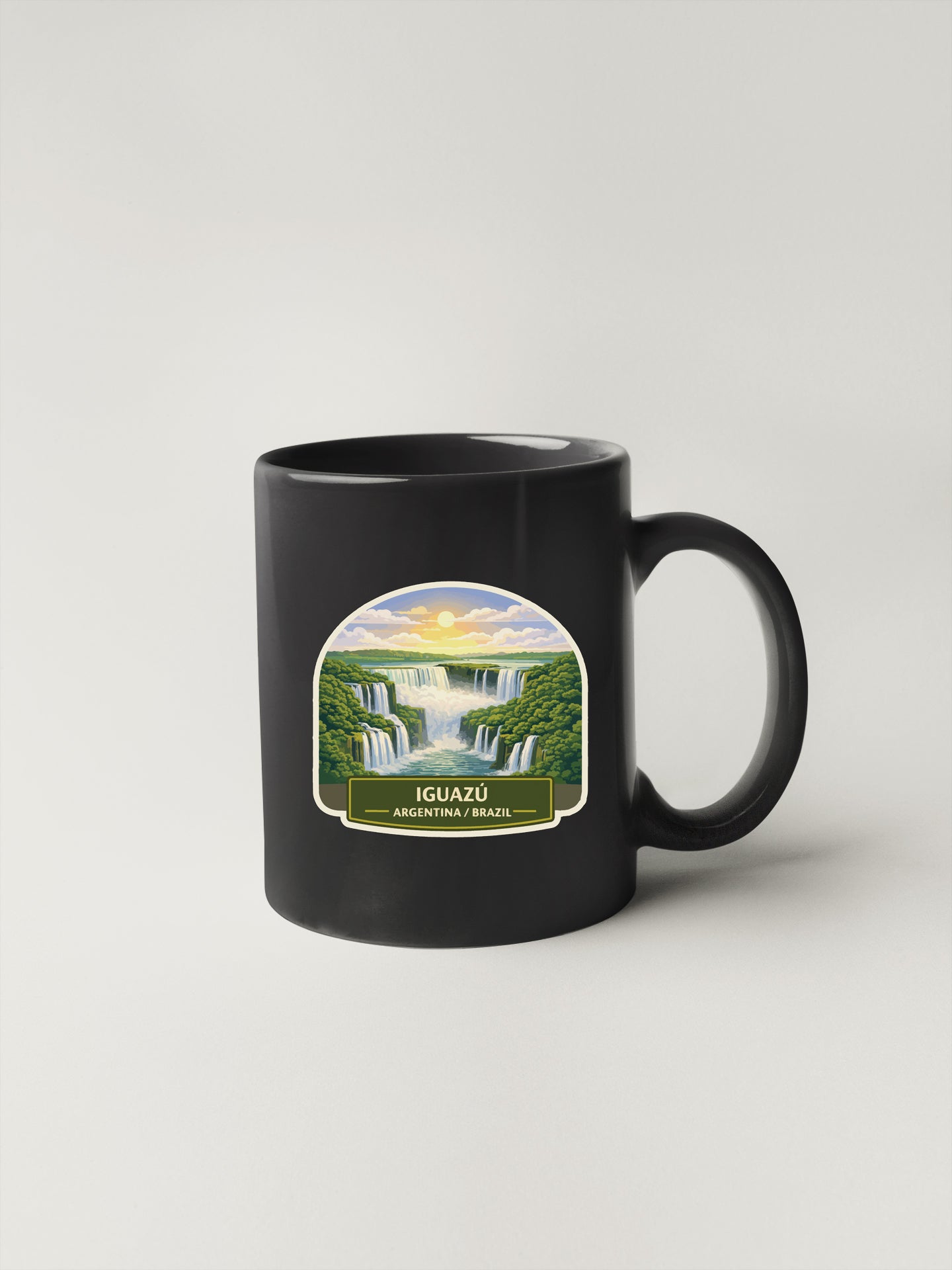 A black coffee mug with a label depicting the Iguazu Falls, a famous waterfall located in Argentina and Brazil.