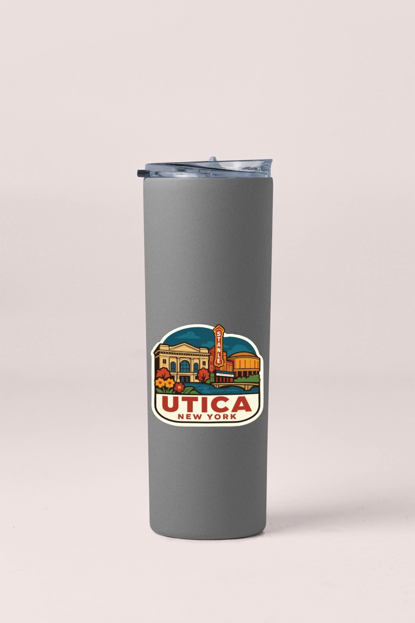 A gray insulated tumbler with a sticker depicting a cityscape and the text "UTICA NEW YORK".