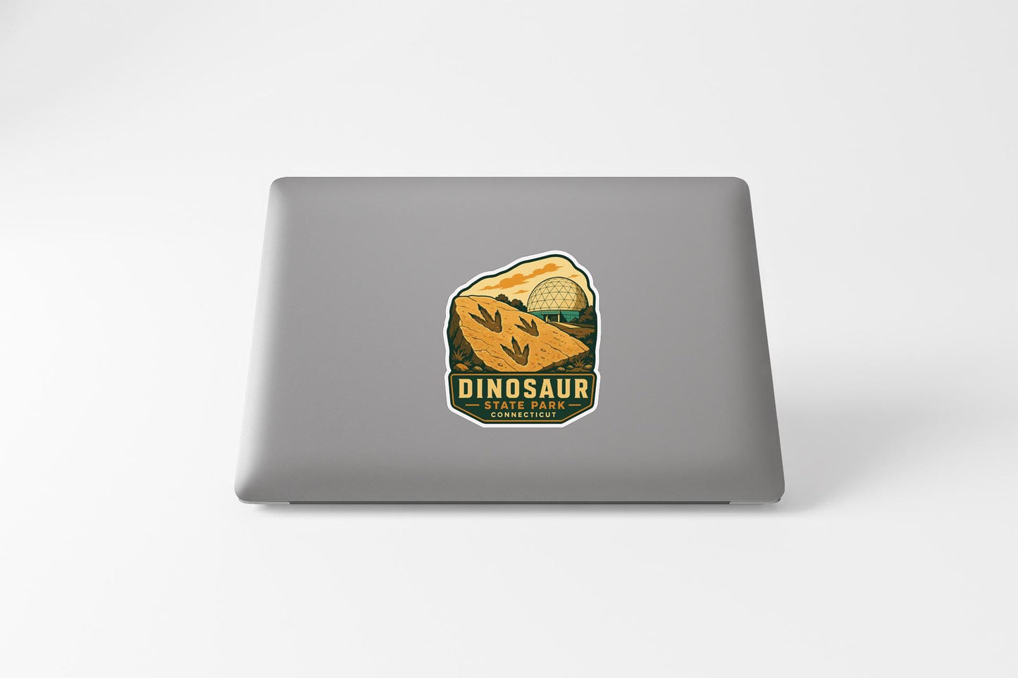 A sticker on the back of a laptop, depicting a dinosaur and the text "DINOSAUR STATE PARK".