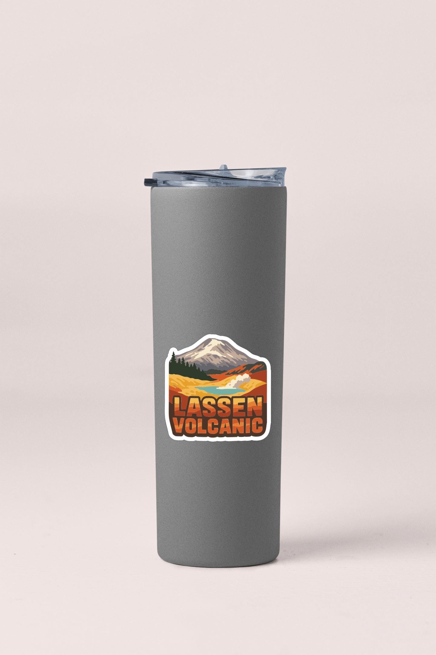 A gray insulated tumbler with a sticker depicting a mountain range and the text "LASSEN VOLCANIC".