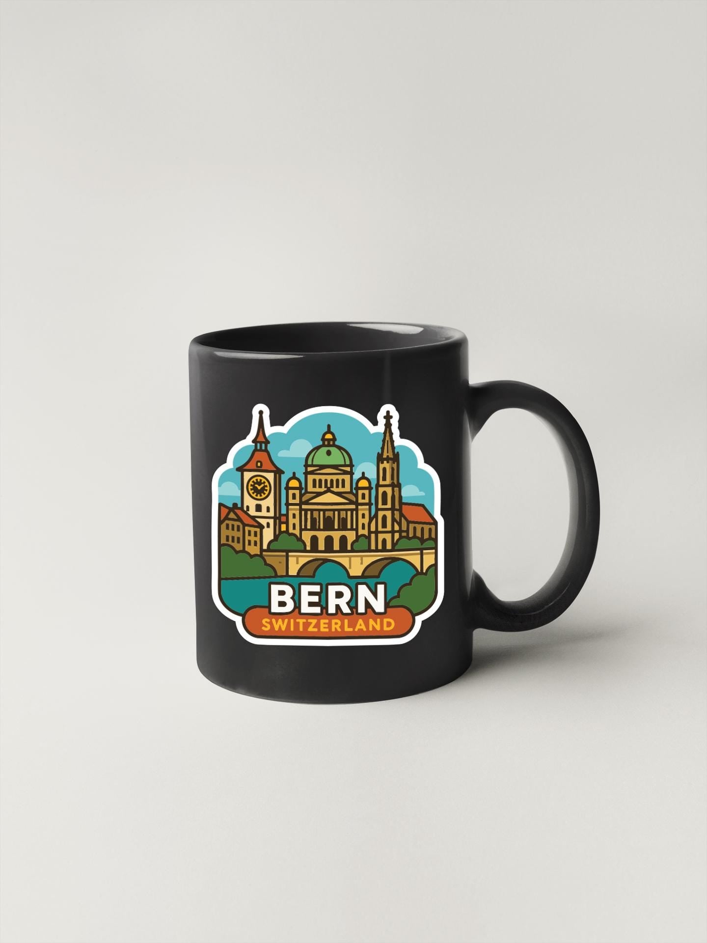 A black coffee mug with a colorful illustration of Bern, Switzerland, featuring landmarks such as the Bern Cathedral and the Swiss Parliament building.