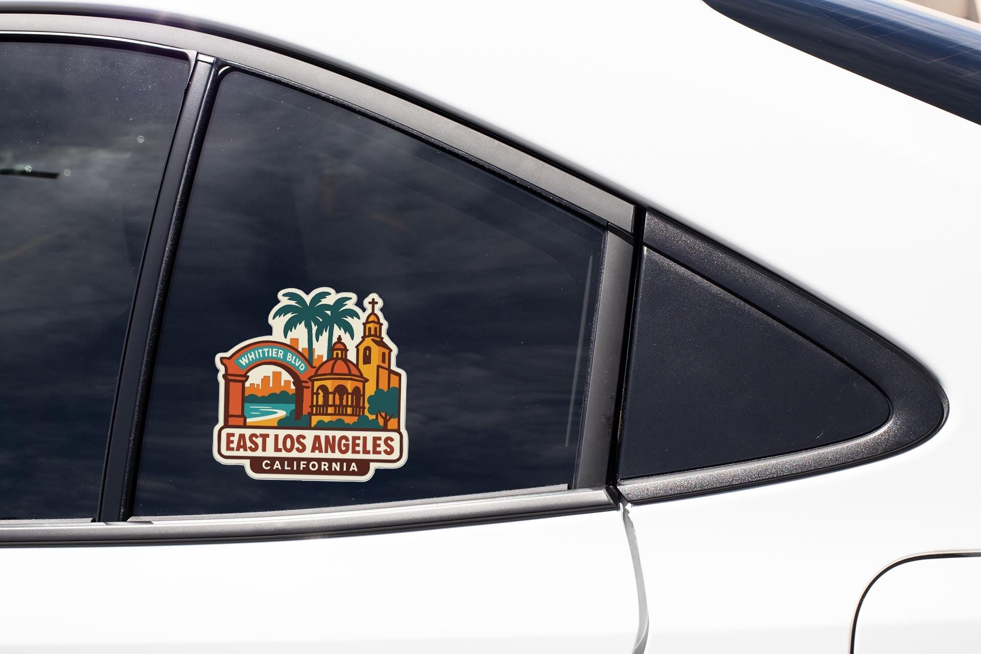 A sticker on the side of a car window, depicting a cityscape with a church and palm trees, along with the text "WHITETER BUNNY" and "EAST LOS ANGELES, CALIFORNIA".