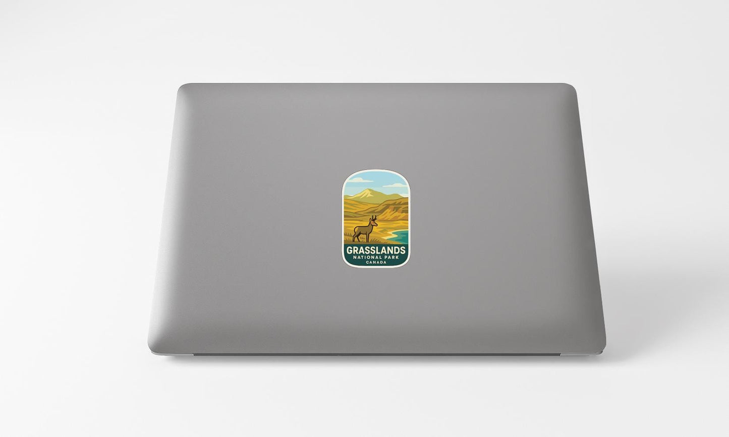 A sticker on the back of a laptop, depicting a scenic landscape with mountains and a river.