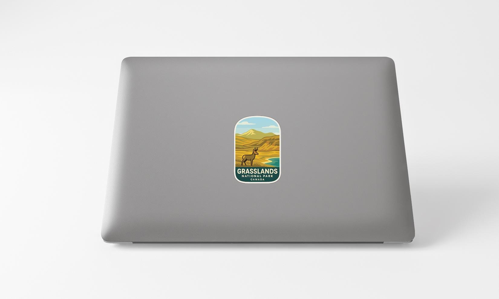A sticker on the back of a laptop, depicting a scenic landscape with mountains and a river.