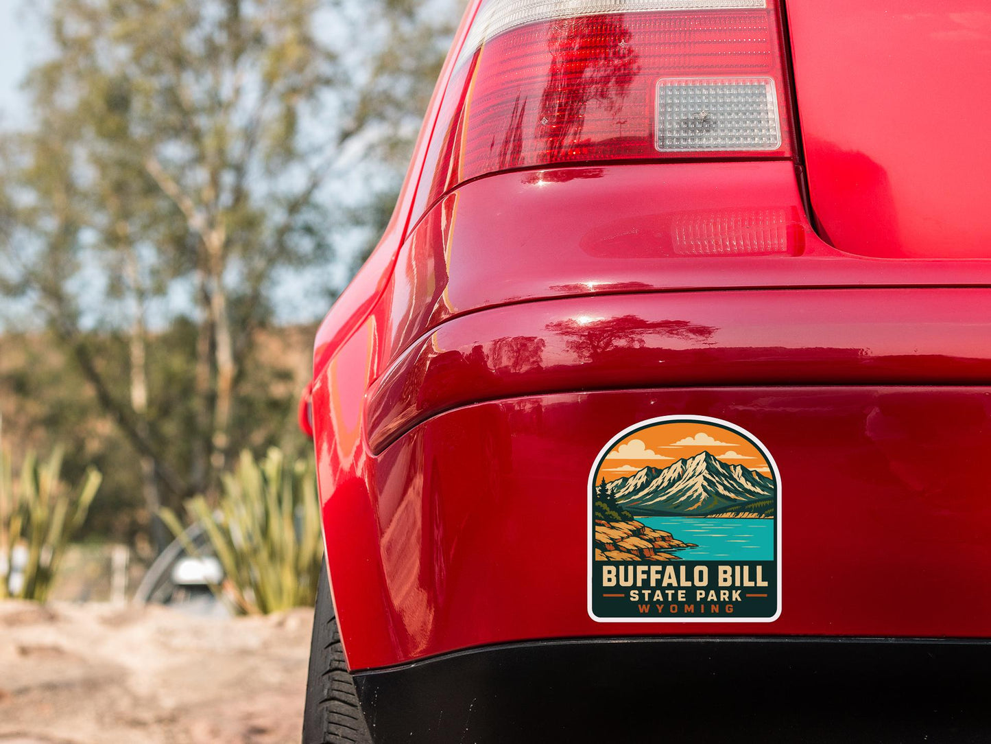 the rear end of a red car with a sticker on the back window that says "Buffalo Bill State Park, Wyoming".