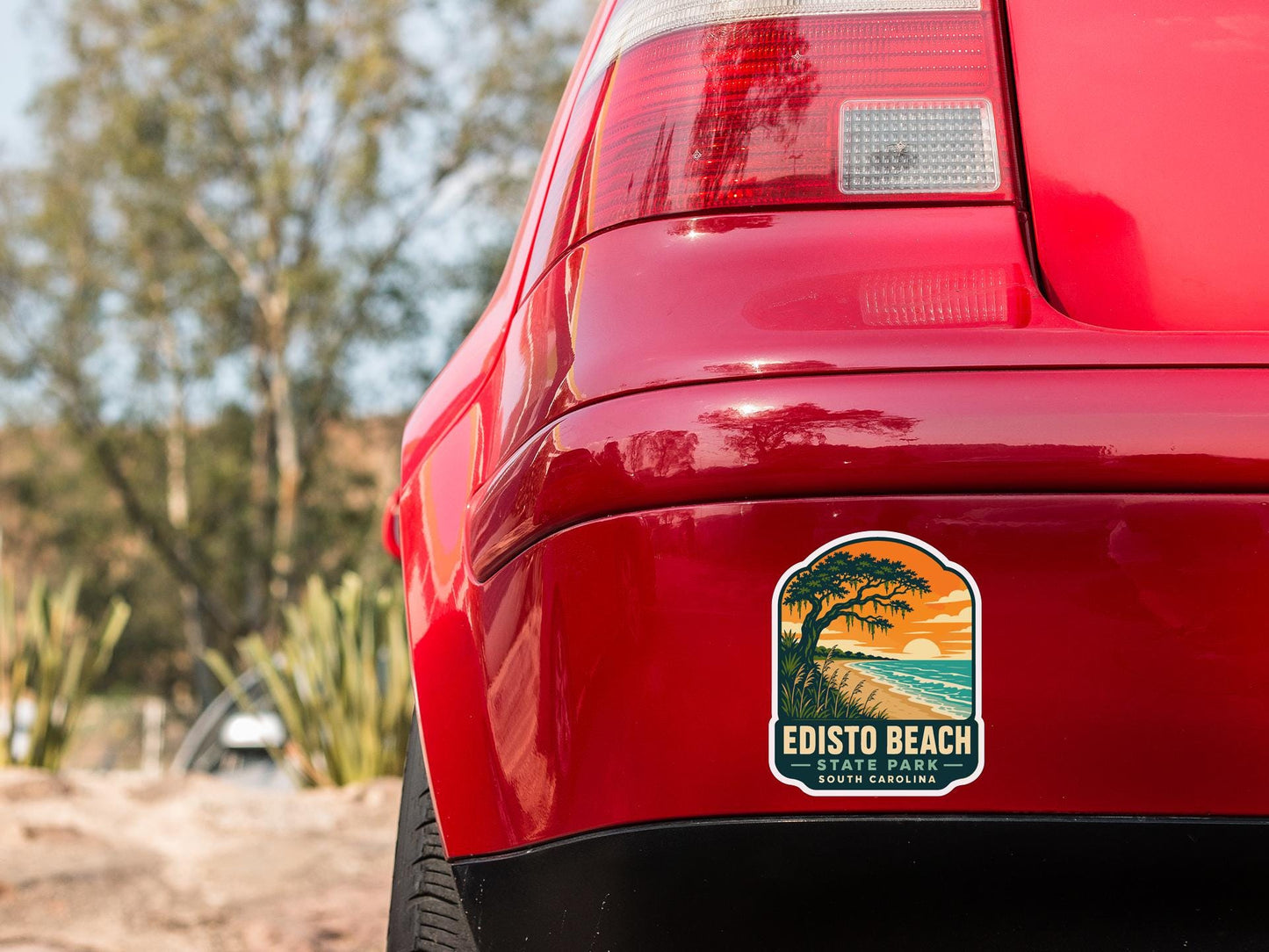 the rear end of a red car with a sticker on the trunk that says "EDISTO BEACH STATE PARK SOUTH CAROLINA".