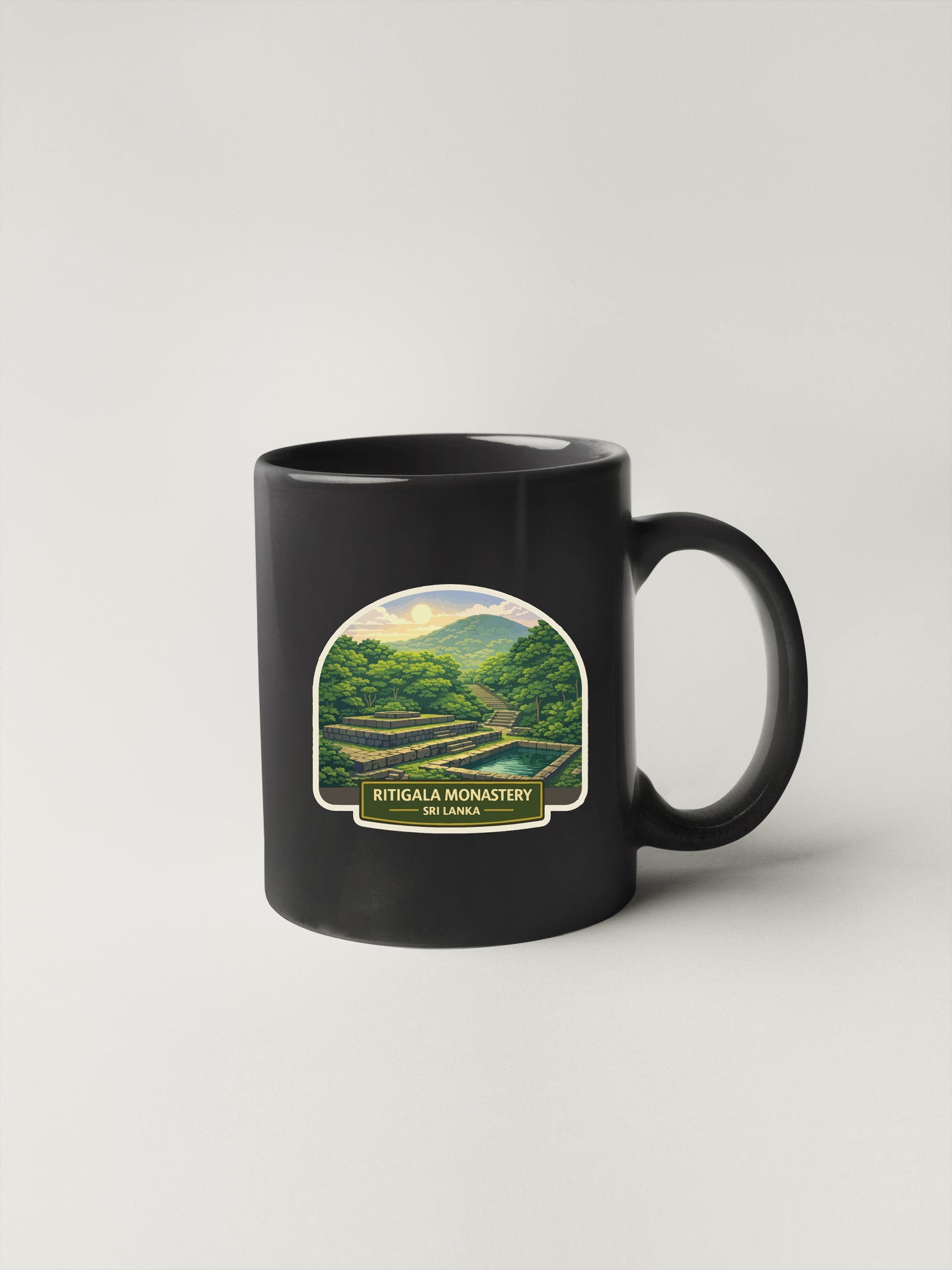 A black coffee mug with a label depicting a scenic landscape, including mountains, trees, and a winding road.