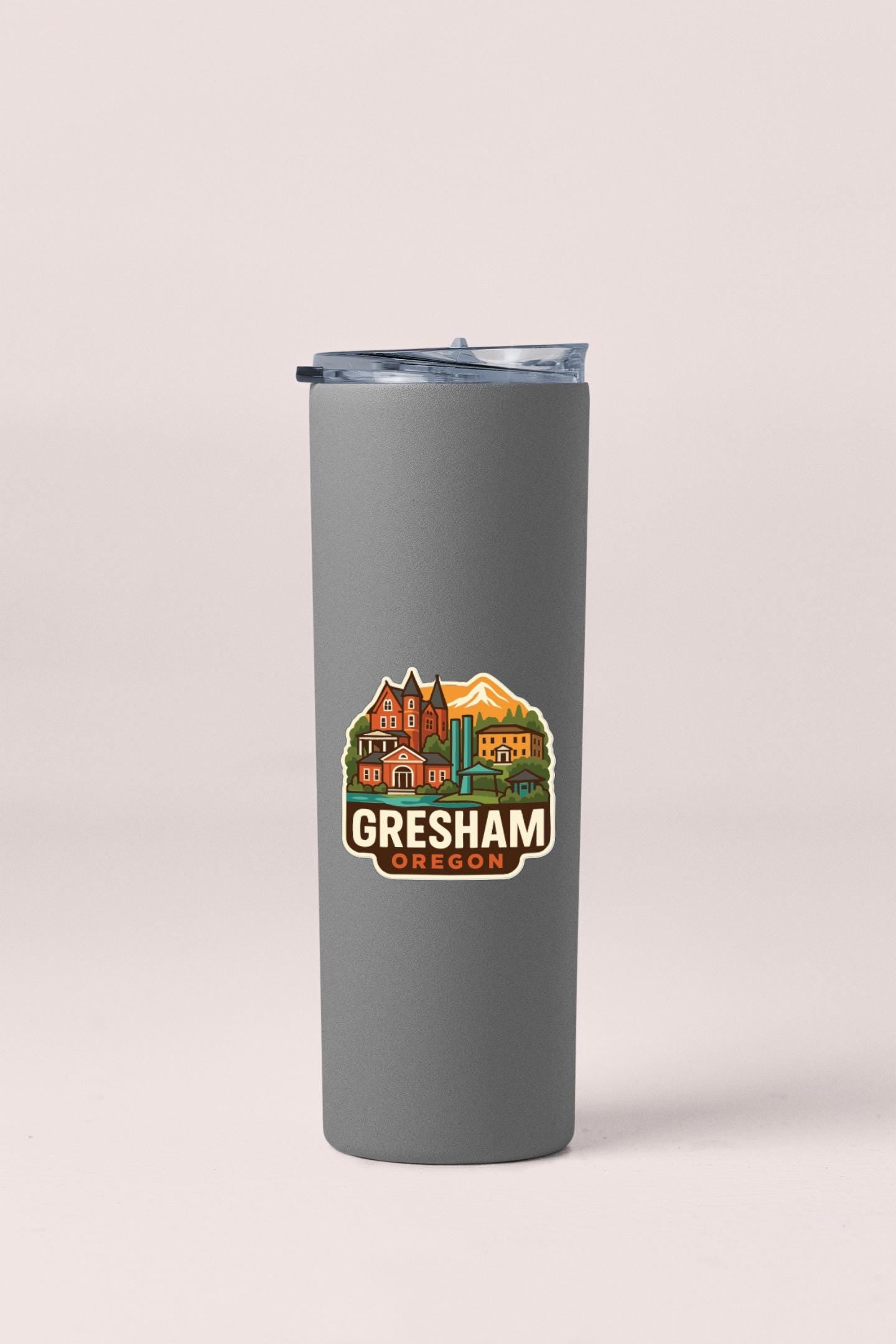 A gray insulated tumbler with a lid and a sticker featuring an illustration of a cityscape with mountains in the background.