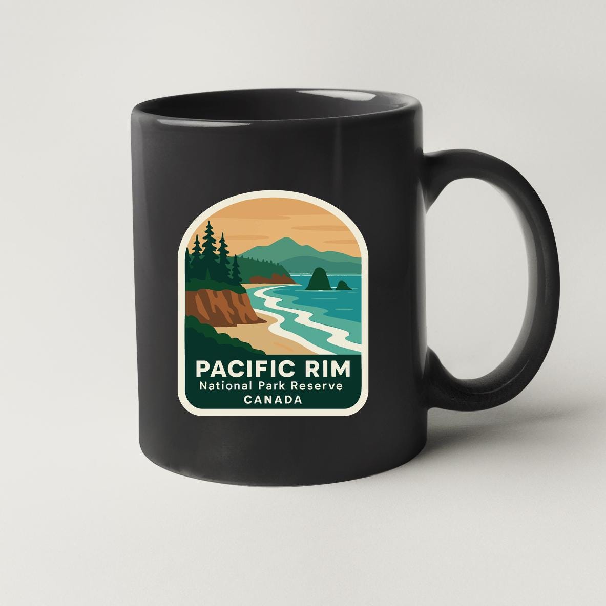 A black coffee mug with a label that features a scenic landscape of the Pacific Rim National Park Reserve in Canada.