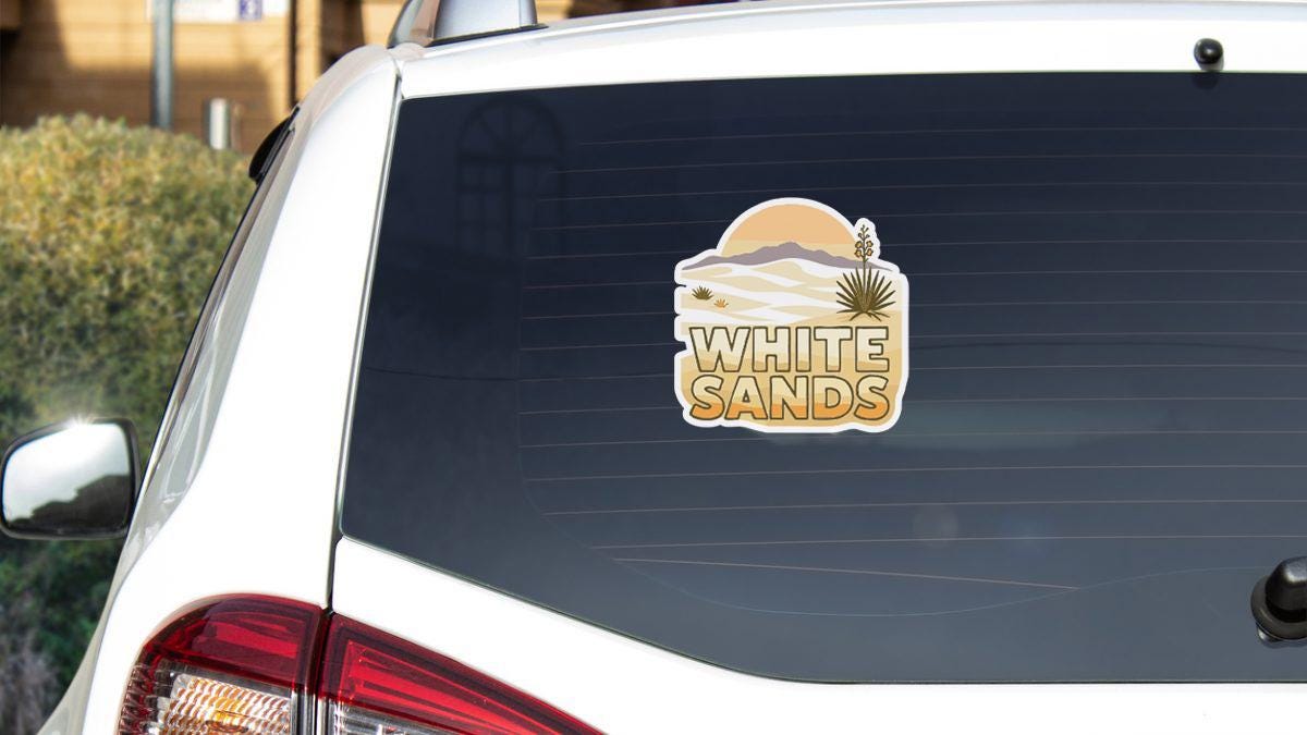 the rear window of a white car with a sticker on it.