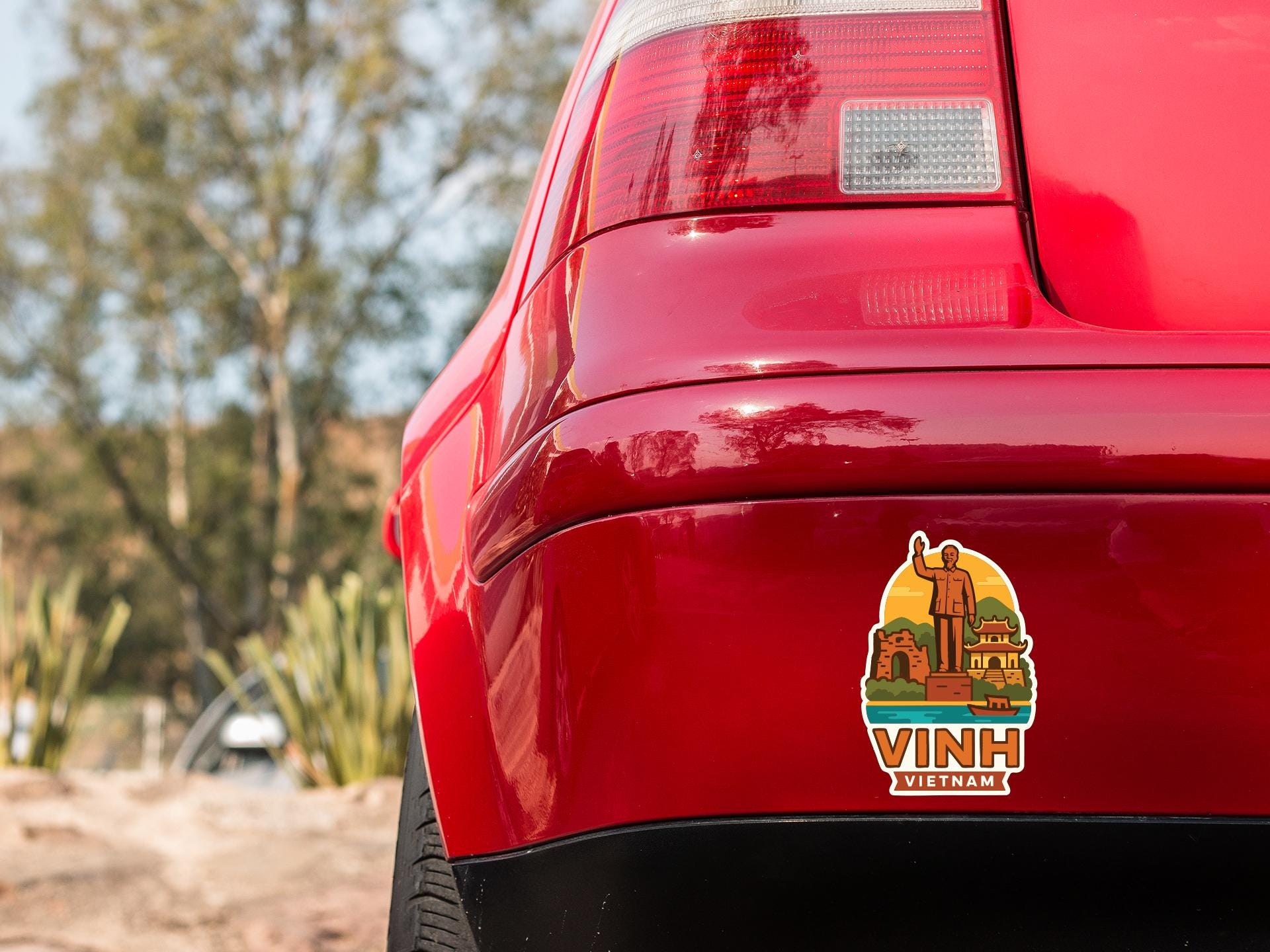the rear end of a red car with a sticker on it, featuring an illustration of a person and a building.