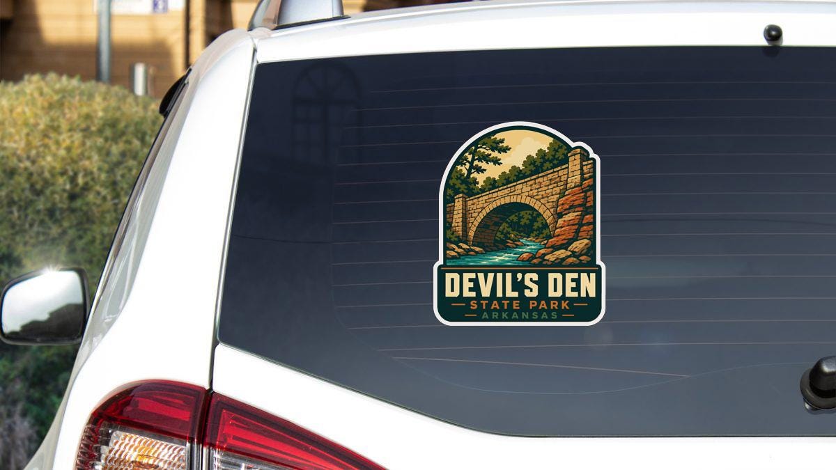 a sticker on the rear window of a white car, depicting a scenic landscape with a bridge and trees.