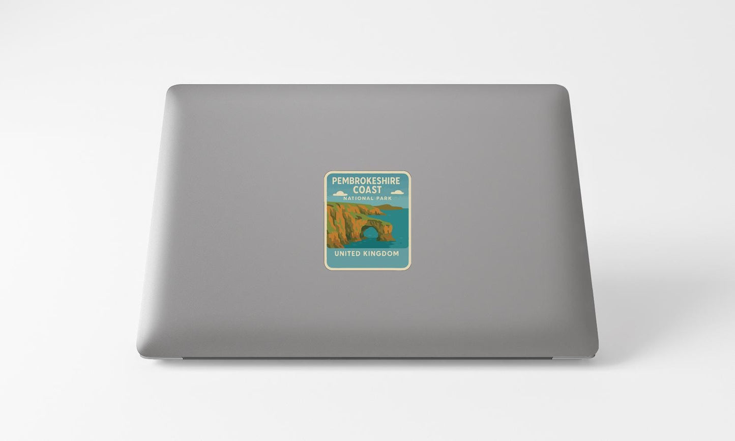a sticker on the back of a laptop, depicting a coastal scene with a castle or monument.