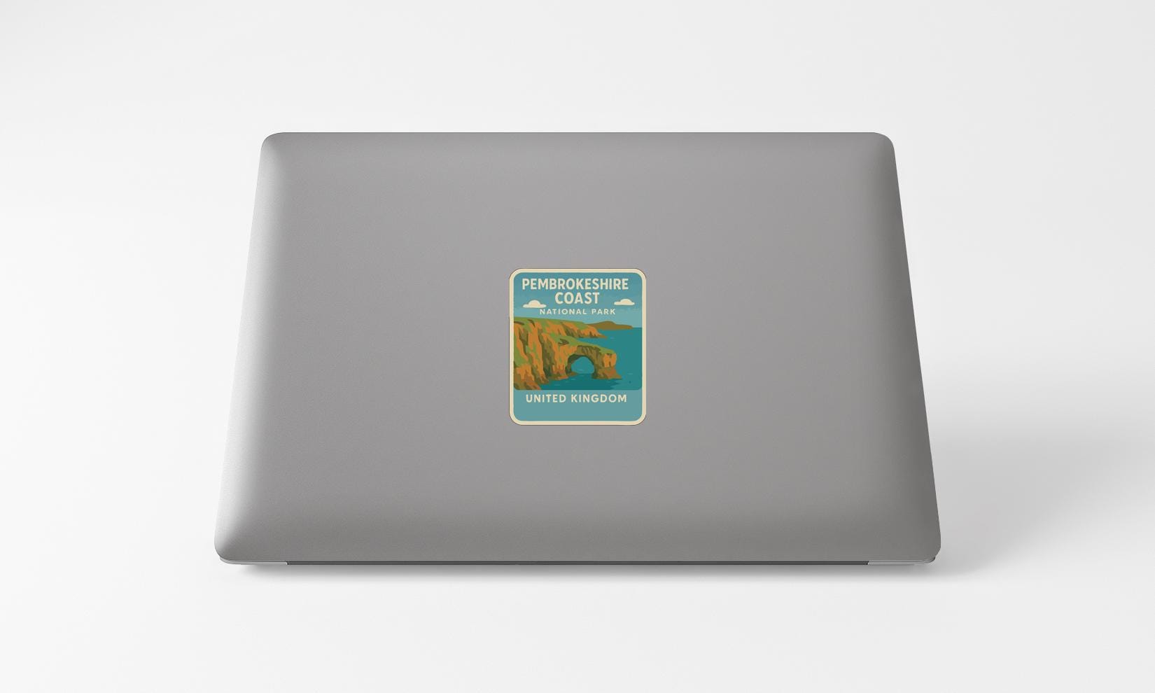 a sticker on the back of a laptop, depicting a coastal scene with a castle or monument.