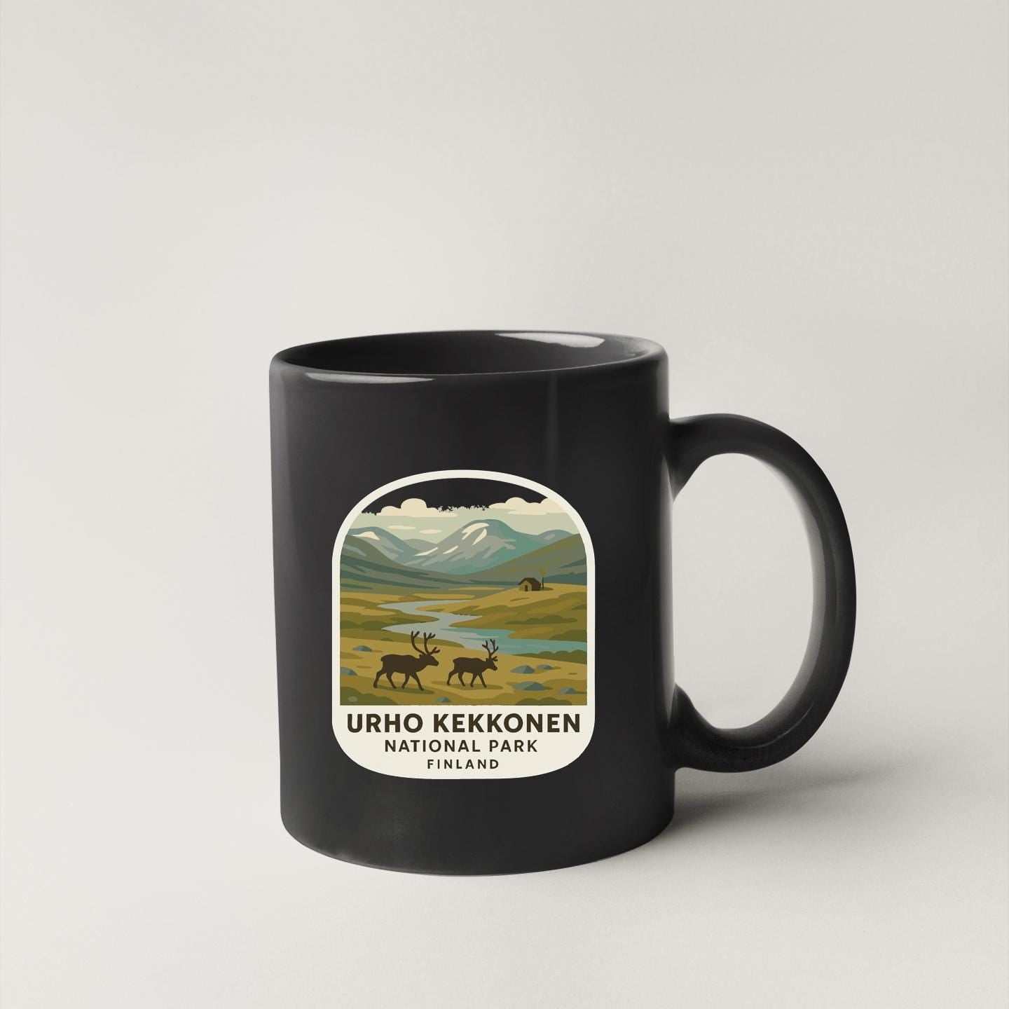A black coffee mug with a label that features an illustration of a scenic landscape with mountains, reindeer, and a river.