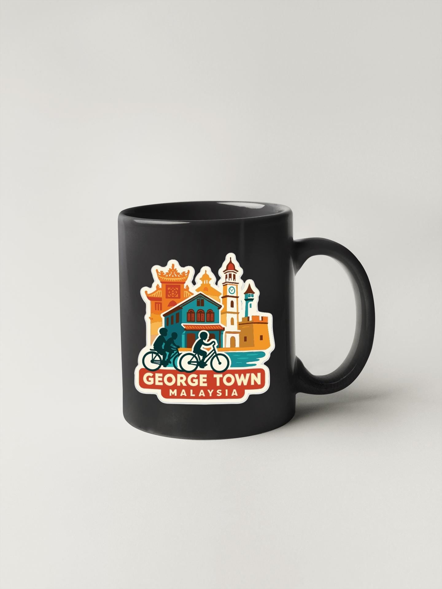 A black coffee mug with a colorful illustration of landmarks and buildings, including a castle, a lighthouse, and a temple, along with the text "GEORGE TOWN MALAYSIA".